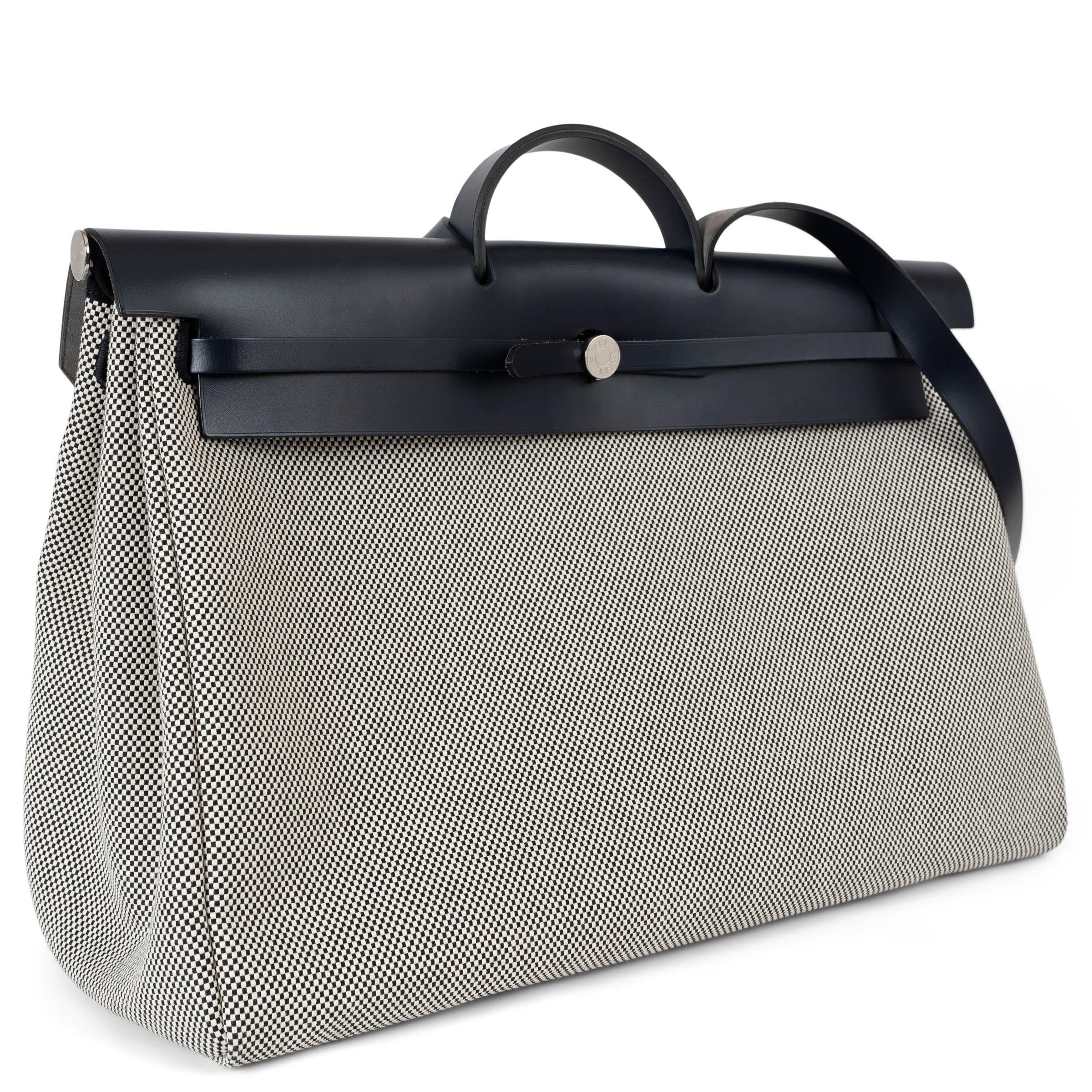 Questa borsa da viaggio Hermès Zip Retourne Cabine 50, autentica al 100%, è realizzata in tela Toile Criss Vikings color crema e nero con finiture in pelle Vache Hunter blu indaco, che combina durata ed eleganza raffinata. Progettata per i viaggi, è