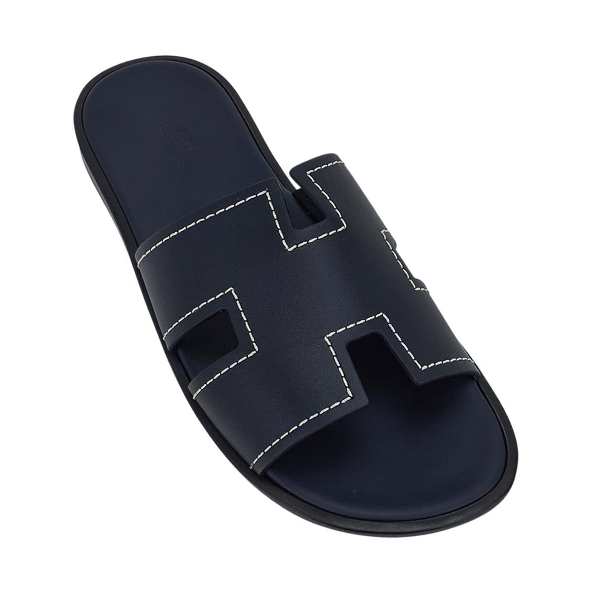 Mightychic offers a pair of Hermes Men's Izmir sandal featured in Bleu Marine.
The iconic H cutout over the top of the foot enhanced with white topstitch.
Sophisticated colours in a silhouette that works for every wardrobe.
Wood heel with leather