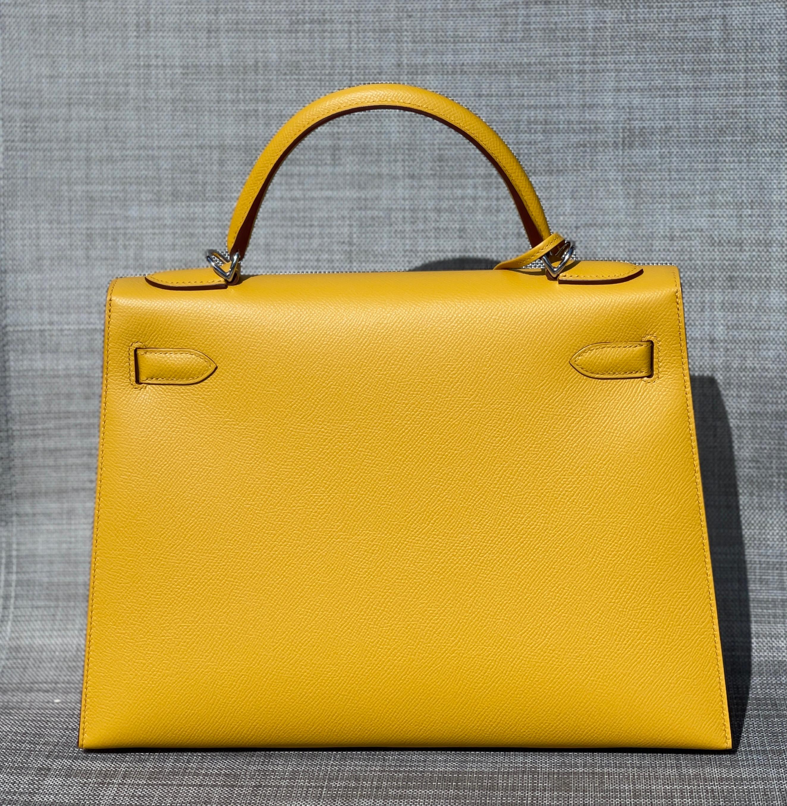 Sac à main Hermès Kelly
32cm
Jaune Ambre Cuir Epsom 
Palladium Hardware
Une magnifique couleur coucher de soleil doré:: Jaune Ambre
L'intérieur est doublé de Chevre et comporte une poche zippée avec une tirette gravée Hermès et une poche ouverte sur