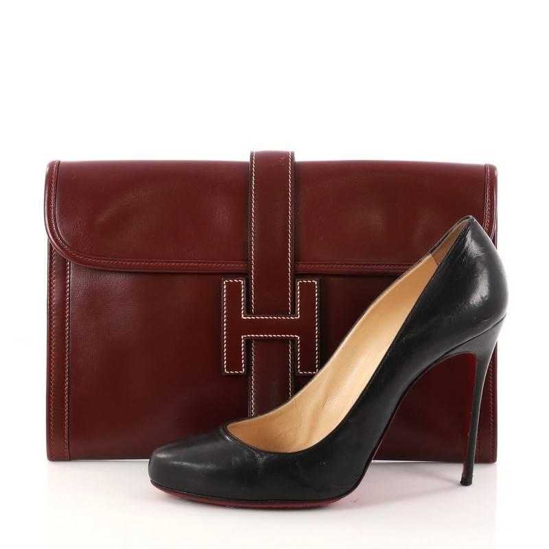 This authentic Hermes Jige Clutch Box Calf PM is the perfect understated everyday accessory. Crafted in luxurious rouge box calf leather, this clutch features a cross-over flap and strap that tucks under the logo H. It opens to a beige fabric-lined