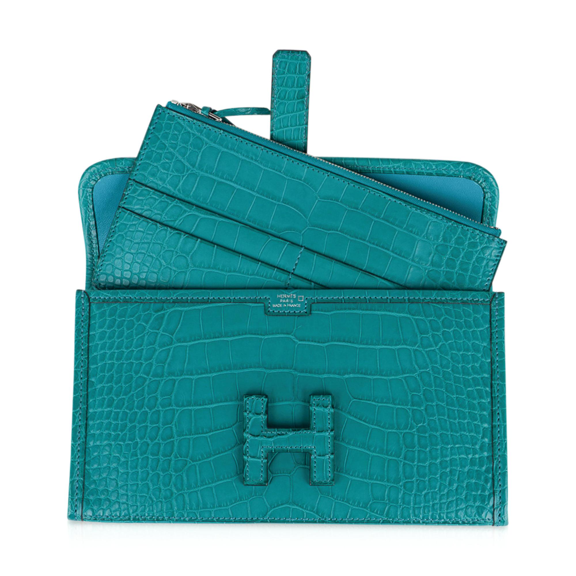 Guaranteed authentic  Hermes Jige Duo Wallet featured in peacock Blue Paon Matte Alligator. 
This stunning Hermes Duo wallet also doubles as a clutch.
Signature H with strap for closure.
Two interior slot pockets. 
Removable change purse with four