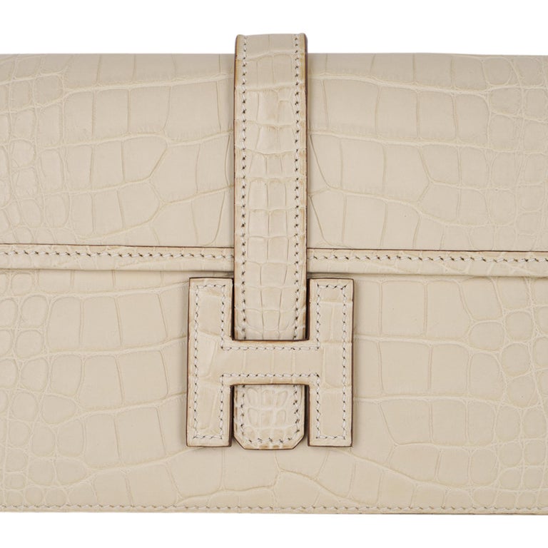 Mightychic offers a guaranteed authentic  Hermes Jige Duo Wallet featured in neutral perfection Vanille Matte Alligator. 
This stunning Hermes Duo wallet also doubles as a clutch.
Signature H with strap for closure.
Two interior slot pockets.