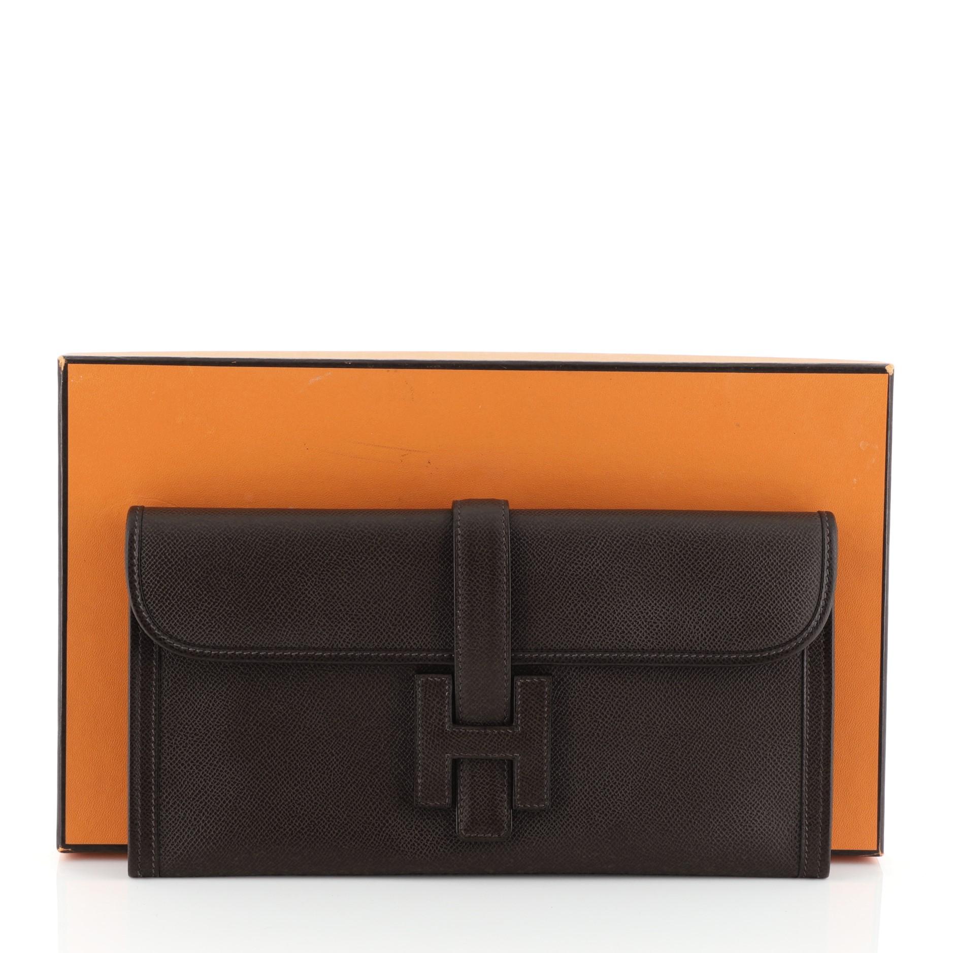 This Hermes Jige Elan Clutch Epsom 29, crafted in Chocolate brown Epsom leather, features a cross-over flap and strap that tucks under the logo H. It opens to a Chocolate brown Chevre leather interior. Date stamp reads: J Square (2006). 

Estimated