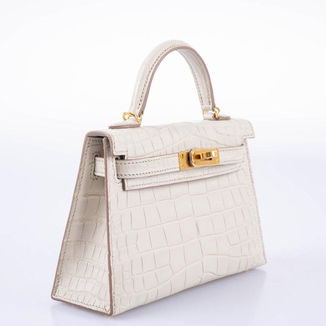 Hermès Kelly 20 Mini II Sellier Beton Matte Alligator with Gold Hardware

The Mini Kelly II is a true masterpiece of craftsmanship and luxury. Its iconic silhouette, with its signature Kelly lock and curved top handle, is a testament to Hermès'
