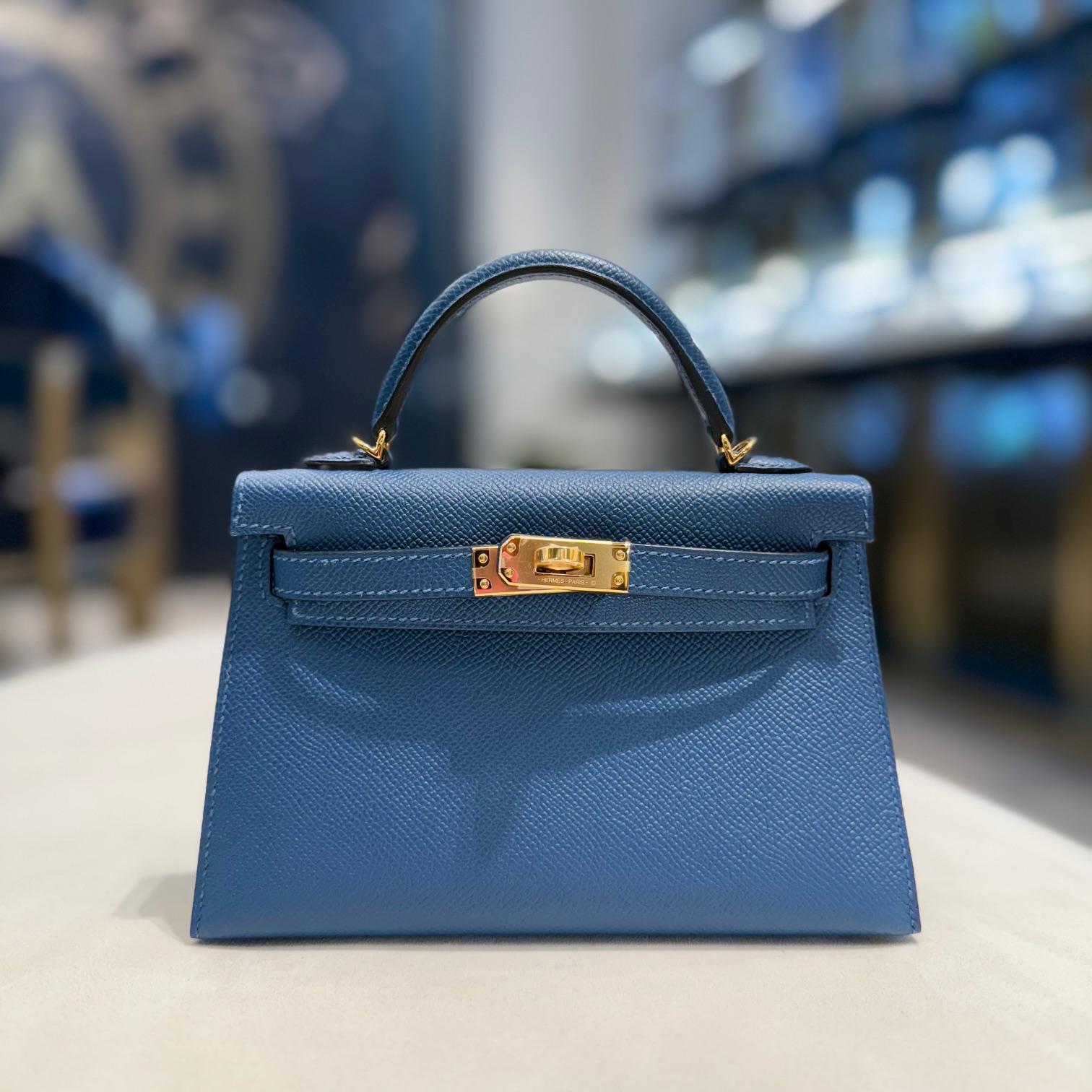 Jewels Aficionado propose le Mini Kelly 20 Sellier Deep Bleu d'Hermès en cuir d'Epsom, un chef-d'œuvre raffiné dans une riche teinte bleu nuit. Associé à des ferrures dorées, il dégage une sophistication et une élégance intemporelles. Structurée