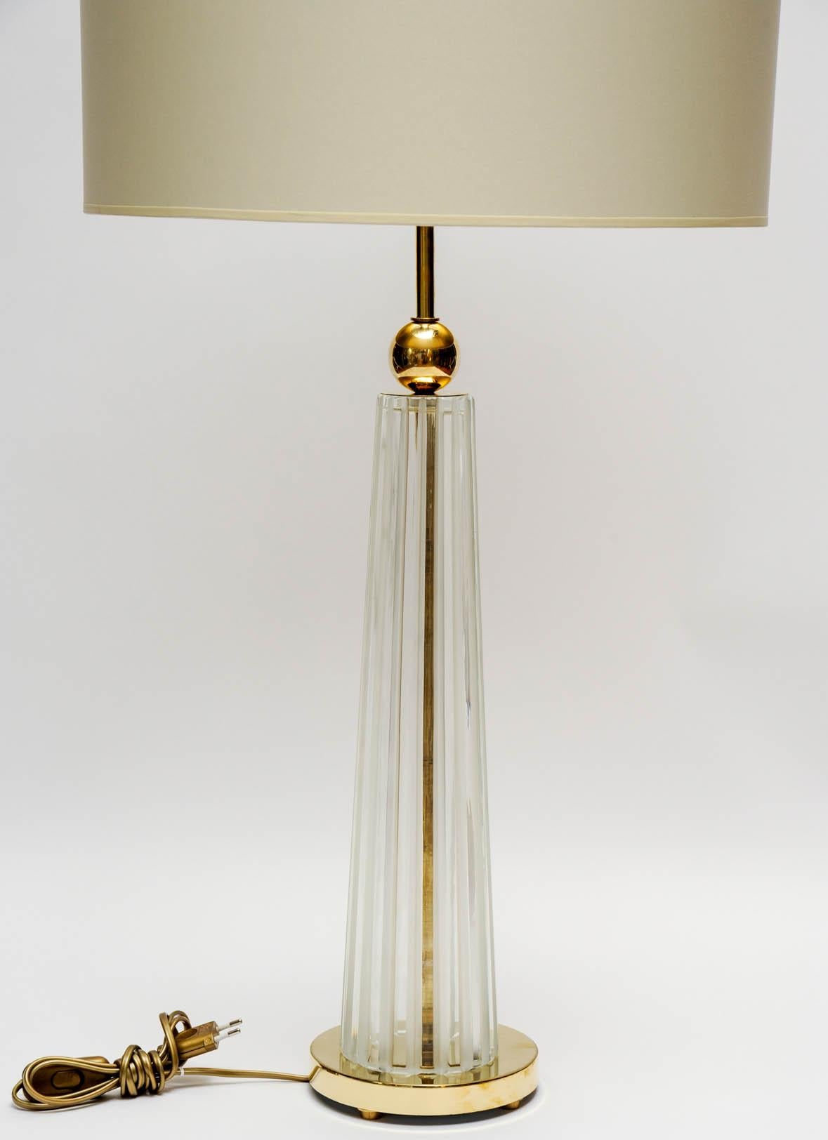 Pair of chic table lamps made of brass feet and clear ridged Murano glass body for an overall Art Deco shape.