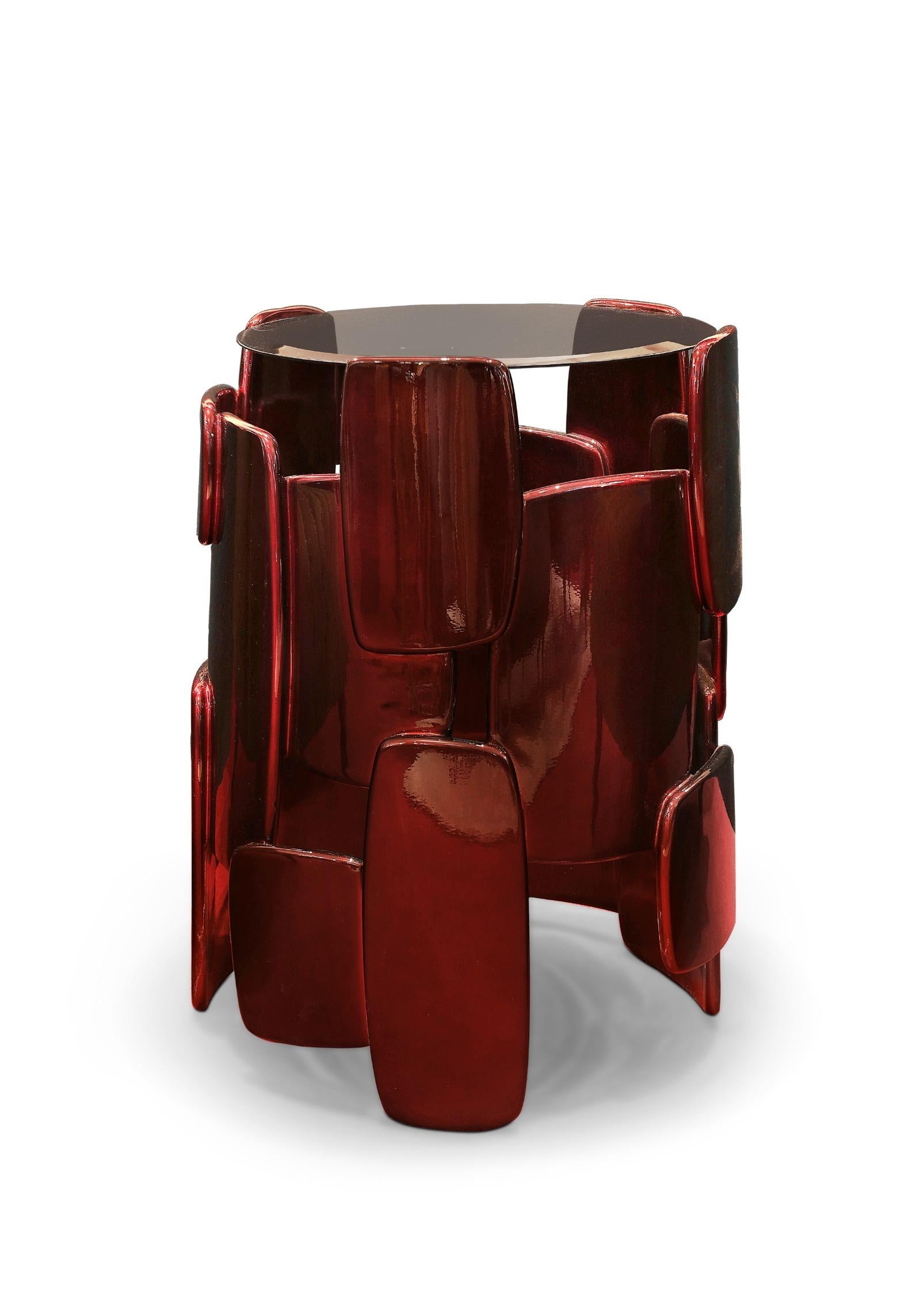 Goroka is known for their dazzling explosion of color and feathers as a way to impress the enemy. GOROKA side table takes inspiration from this tribe located in Papua New Guinea. It is coated with silver leaf with shades of translucent red and a