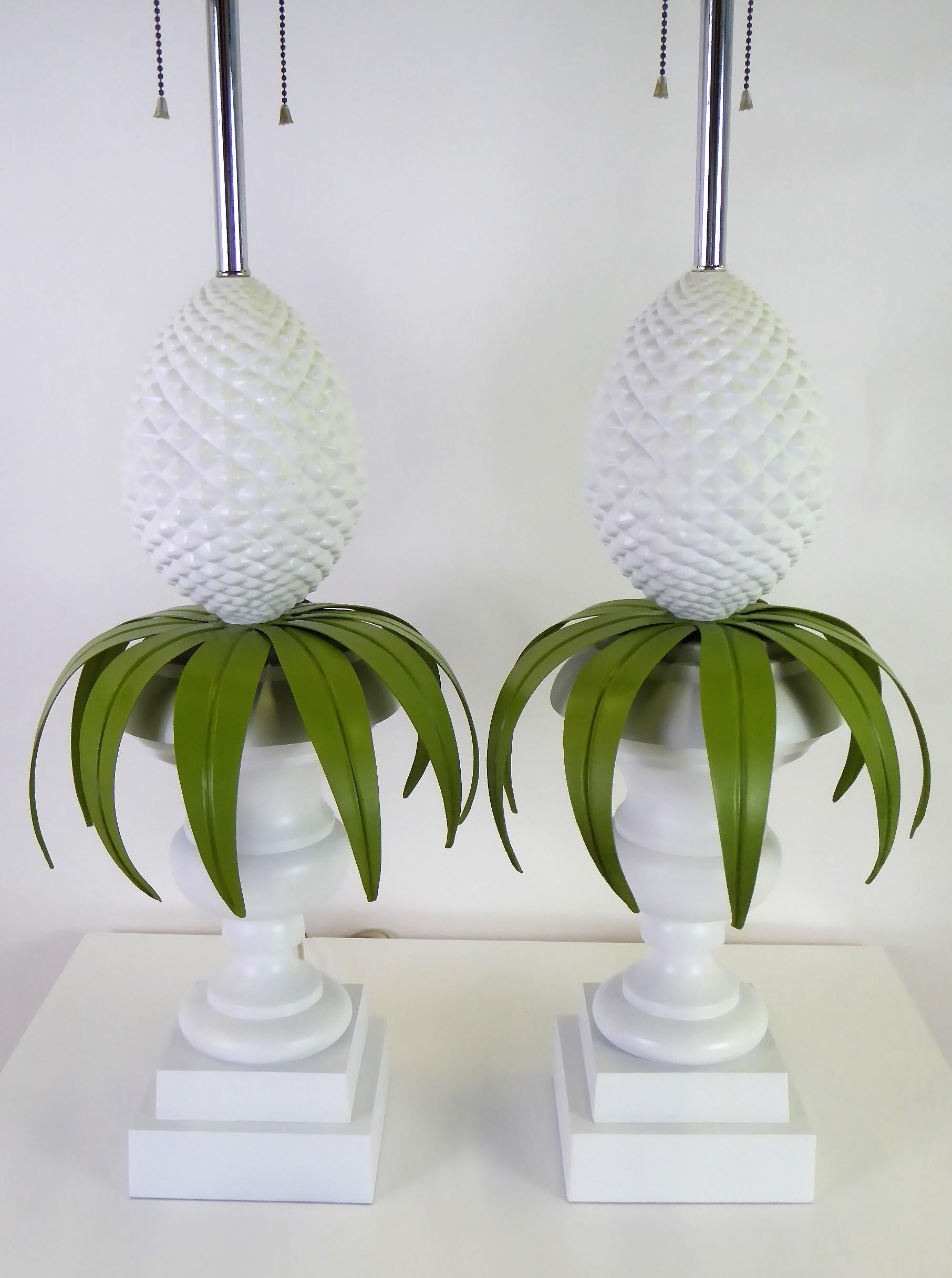 Dynamic and exceptional pair of lacquered metal topiary table lamps by Norman Perry Inc. featuring a pineapple in urn topiary, all white with green leaf follage. Long the symbol of hospitality, the pineapple reigns here. Very Palm Beach, Palm