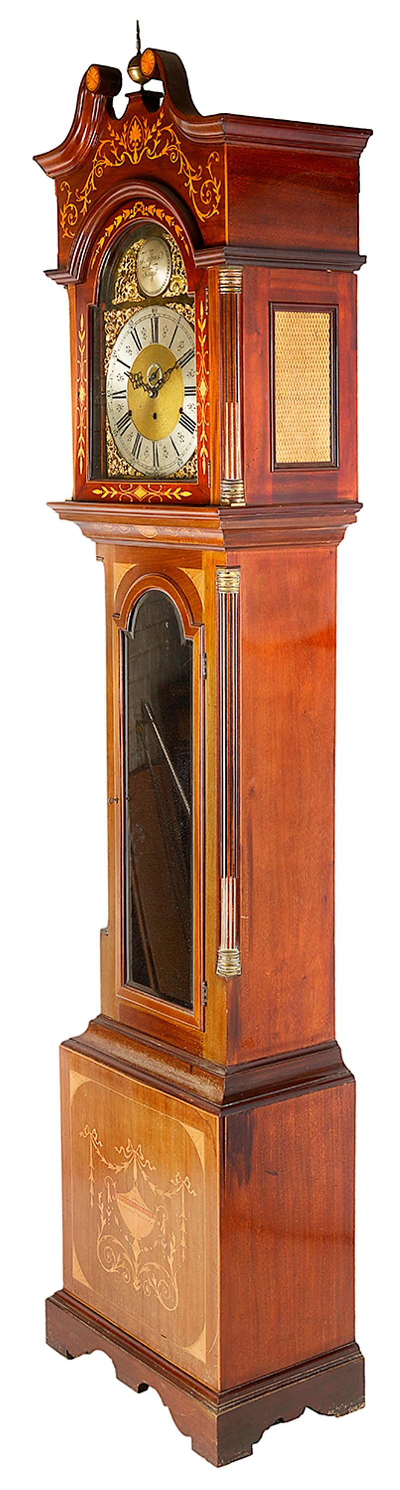 A very impressive late 19th-early 20th century Sheraton Revival mahogany musical grandfather clock, having marquetry inlaid to the hood and case of scrolling foliate and motif decoration. The three train brass faced arch dial with a strike, silent