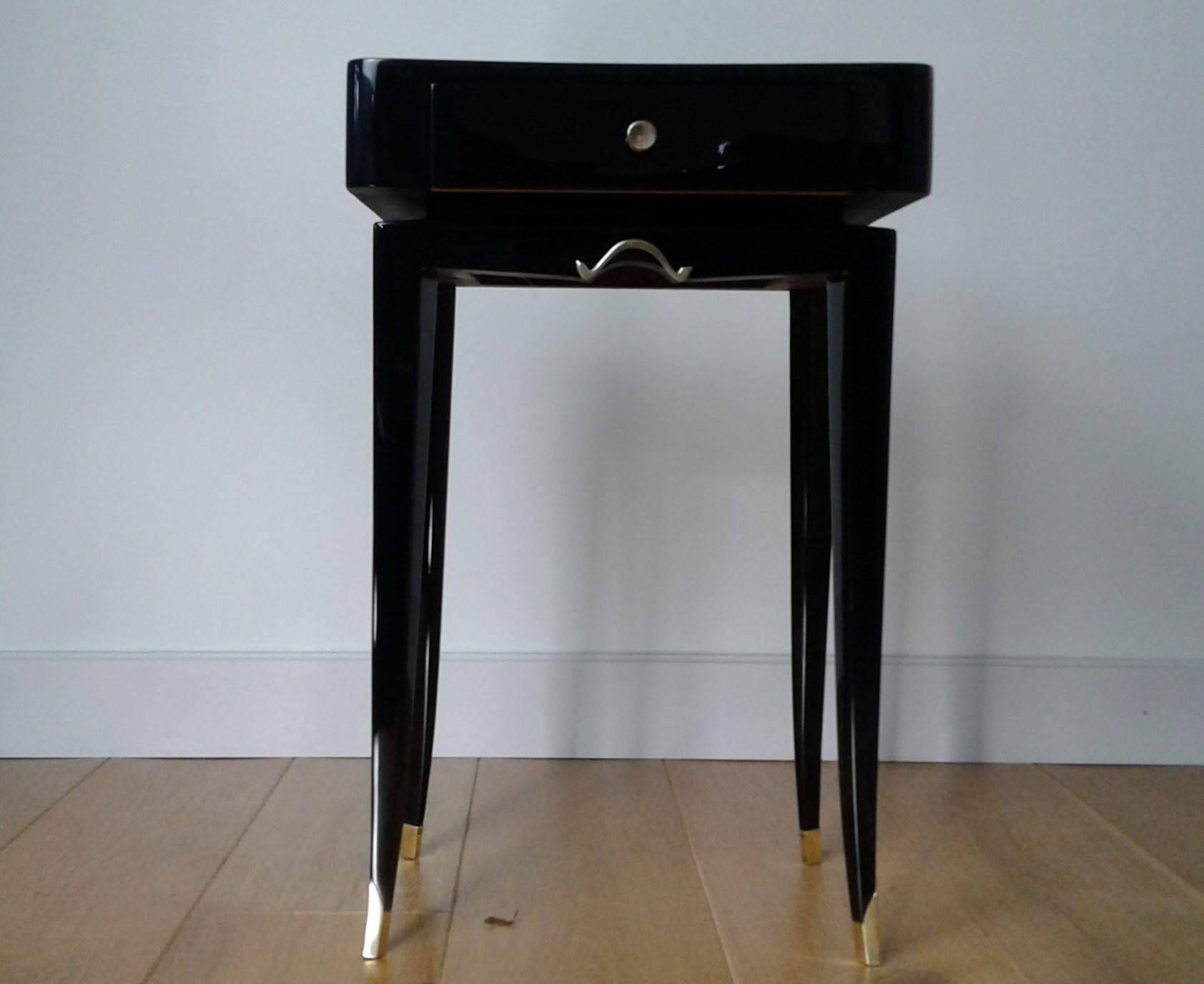 Pair of black lacquered bedside tables or end tables made of a black lacquered rectangular pedestal resting on four saber feet ending with brass shoes.
A drawer is set on the front. It opens with a brass handle and serves as storage.
Fully