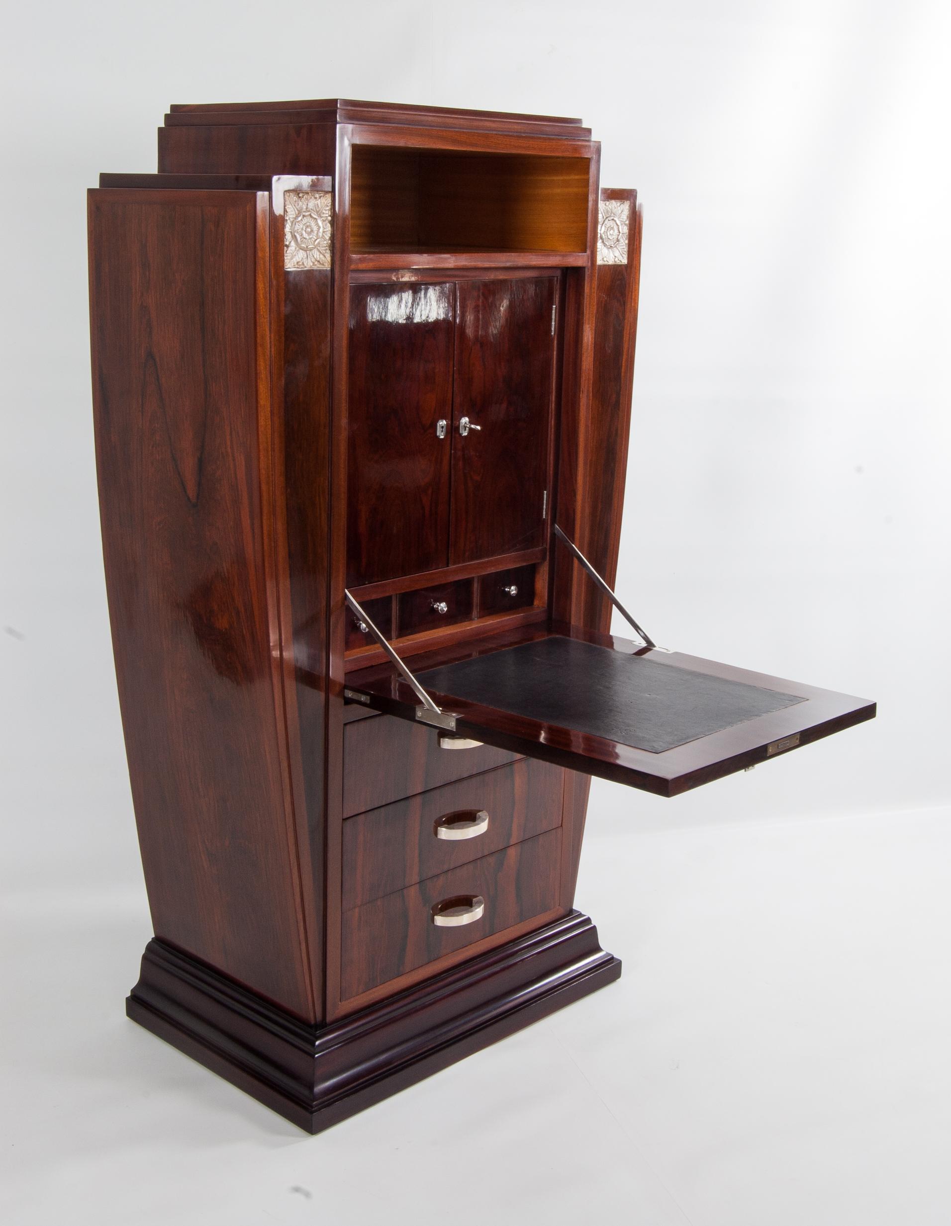 This impressive French Art Déco cabinet was manufactured in the 1920s. 

The imposing structure combined with the rosewood exterior and the mahogany interior makes this a very beautiful piece of art. The skillfully crafted silver plated ornaments