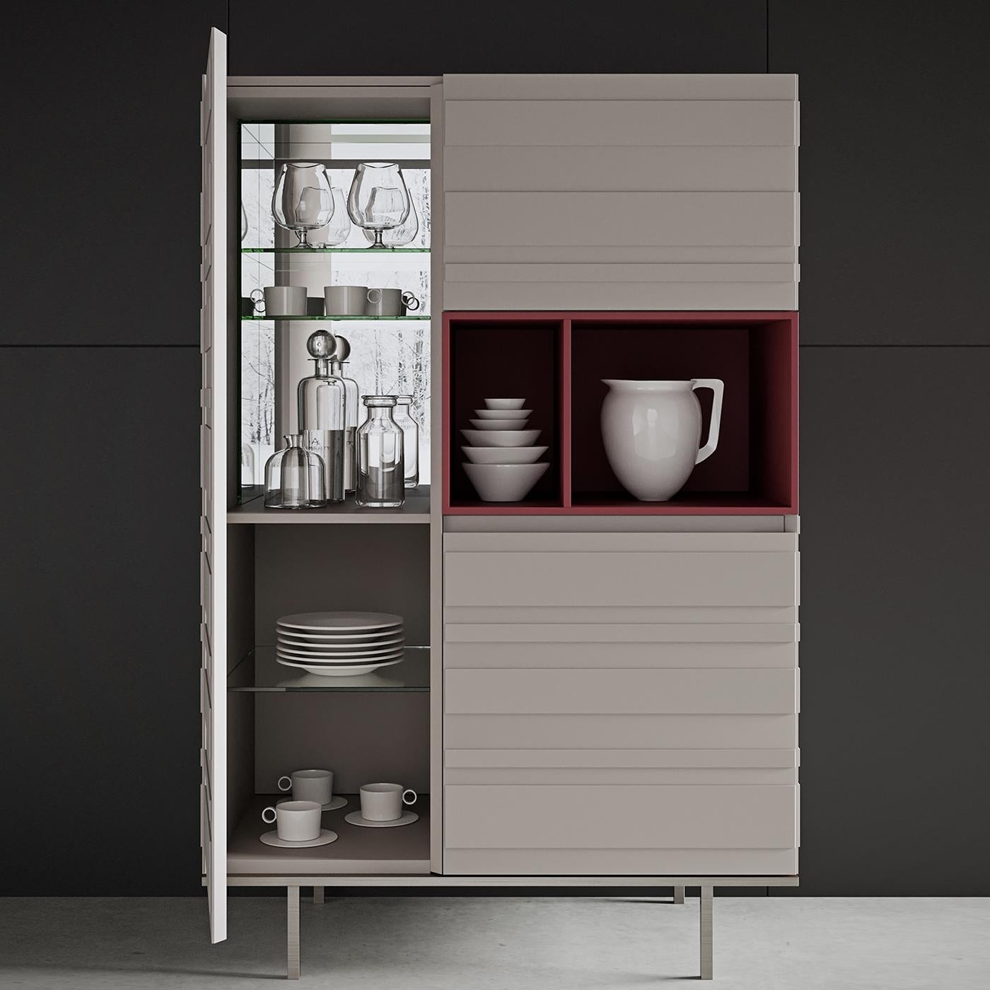 This cupboard features three doors and a two-part open compartment with a ruby red matte finish. The matte linen finish of the strikingly textured surface of the piece, whose horizontal stripes give their name to the collection, adds a unique