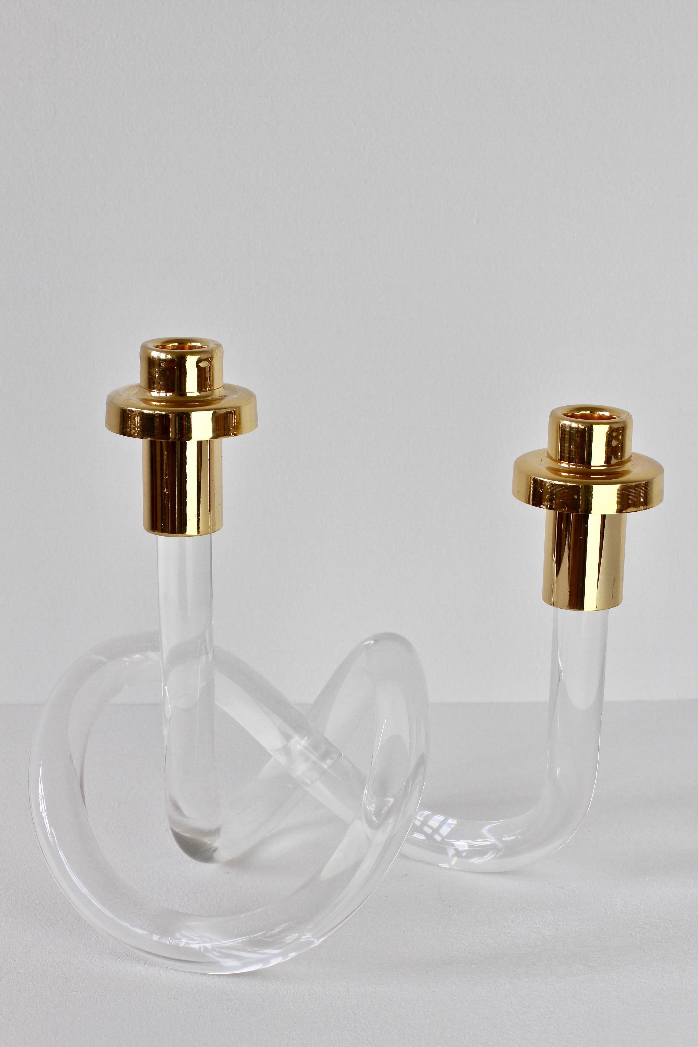 A Lucite and gold-plated brass double candlestick holder/candelabra by American designer Dorothy Thorpe, circa 1940s. With it's use of a single piece bent and twisted acrylic to form the whimsical base, it is often referred to as the 'pretzel'