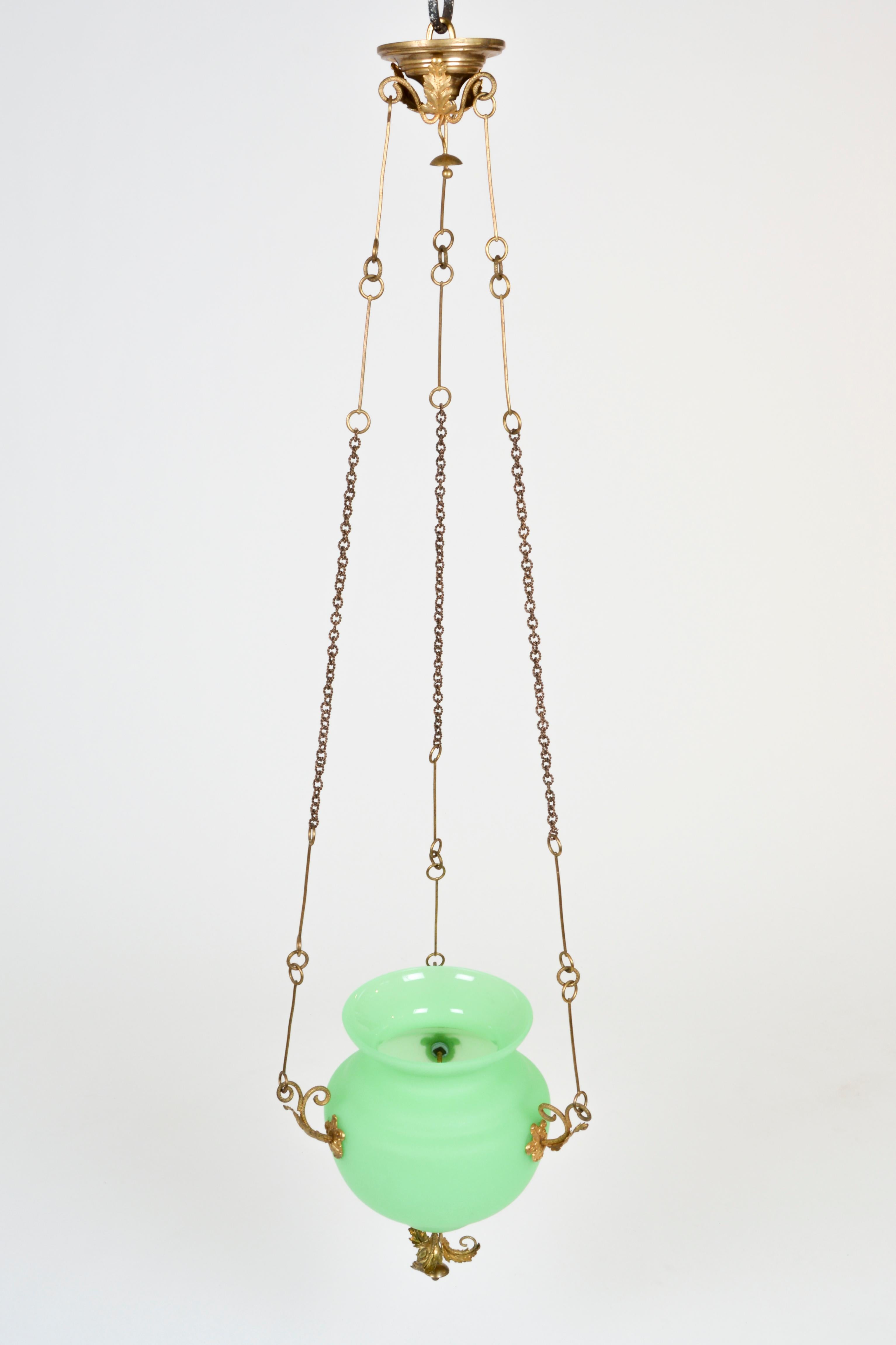 A lovely glass pendant with elaborately embossed brass suspension. The vase is of opaque glass of a striking green, typical for the period.
It emanates the romantic spirit of the Viennese Biedermeier spirit and fits perfectly in a powder room or