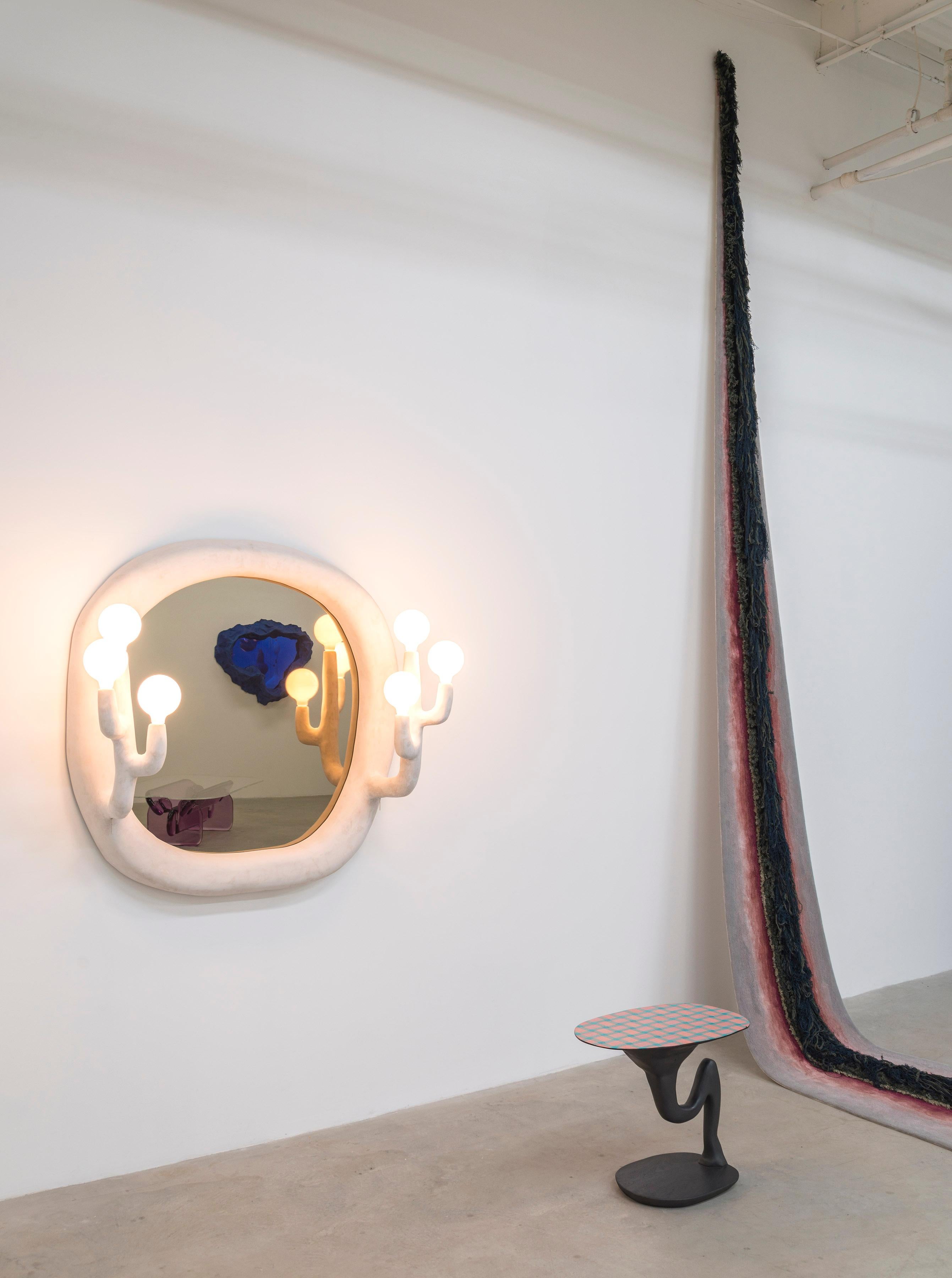 Bronze mirror framed in resin covered foam with two, three-lamp sconces at either end.

1st piece (mirror) title of work: Trinitys / materials: Foam, resin, tinted resin, bronze mirror, electrical components / Size: 48”x 48” x 18” deep /