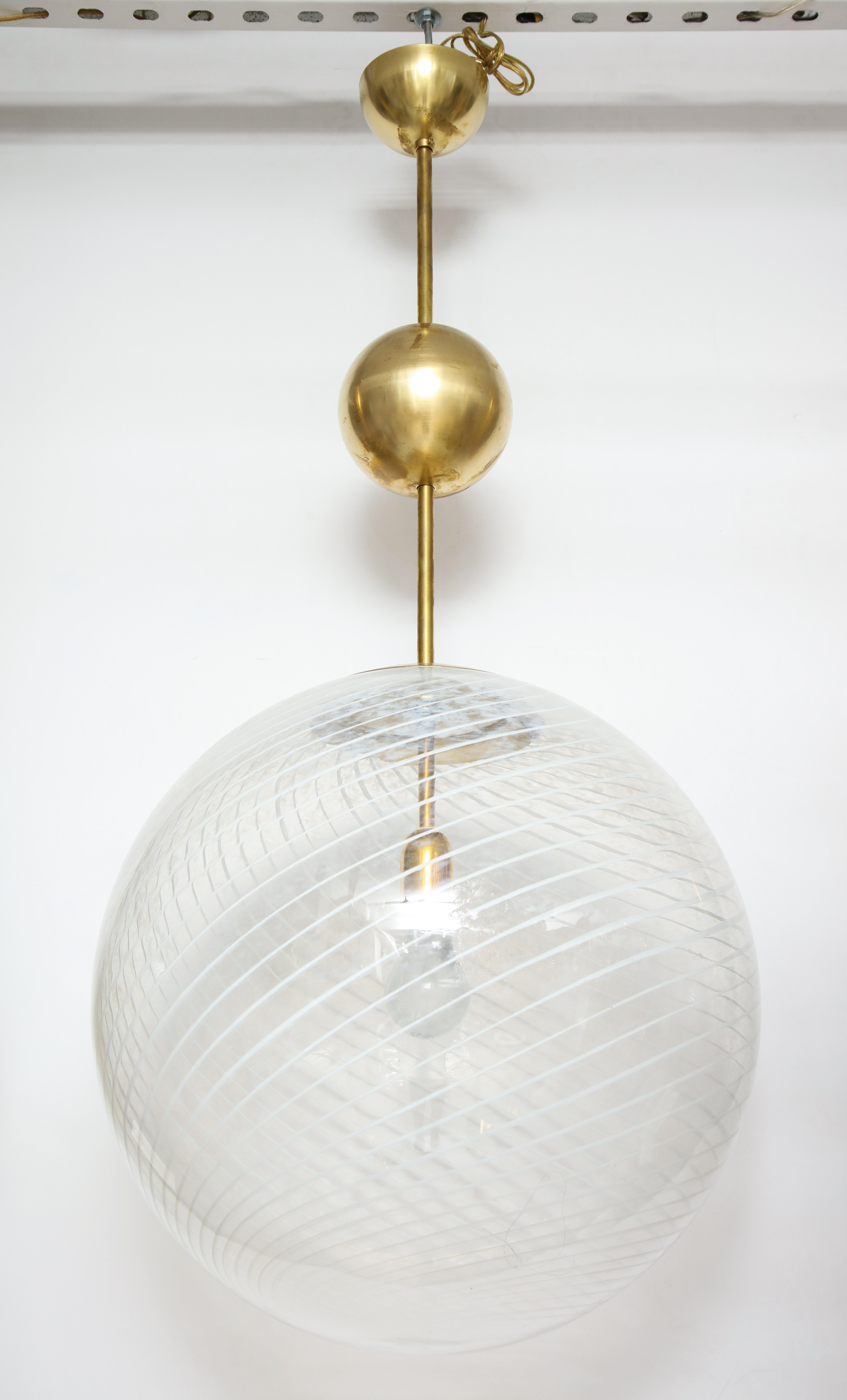 A large Venini mottled white and clear handblown murano glass globe with a cross-hatched pattern suspended from the original stem with brass ball adornment below the canopy, newly wired for the American market with a single Edison socket that can