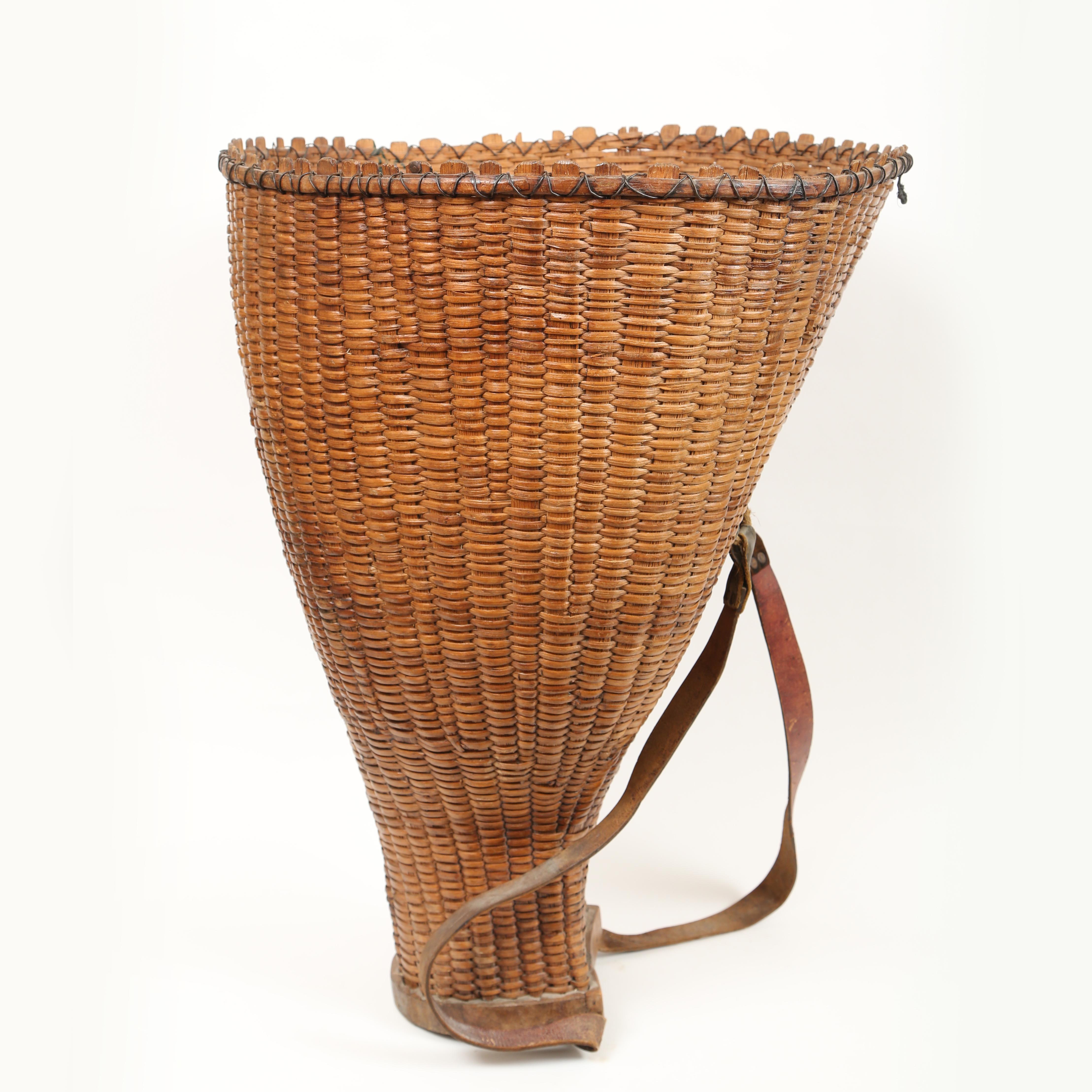 Large 19th century French handwoven grape pickers basket. The leather straps are for carrying the basket on your back. The vertical strapping terminates in the thick wooden bottom. The baskets wonderful form fitting shape is strengthened with wire.