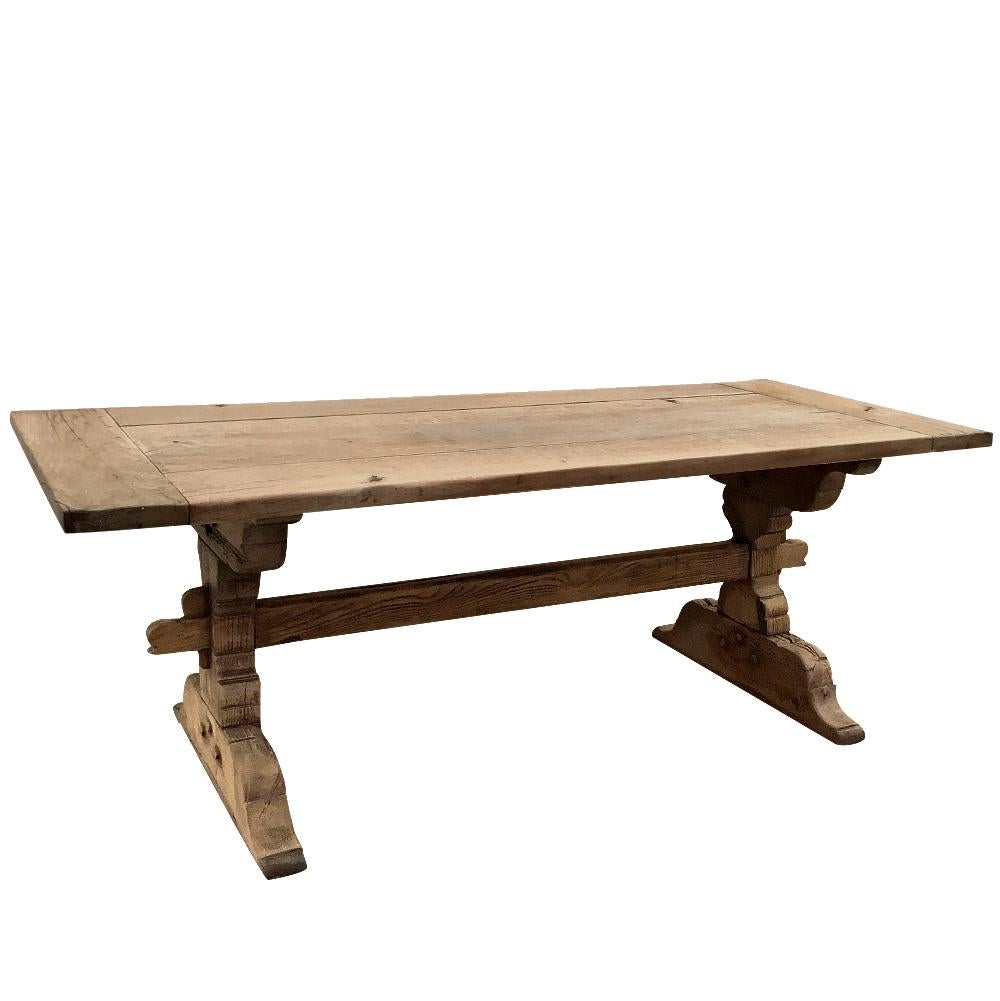 19th century Country French Provincial stripped oak trestle table was rendered from solid, thick planks of old-growth oak to last for generations! Massive sculpted side supports showing pegged mortise and tenon joinery are connected with an equally