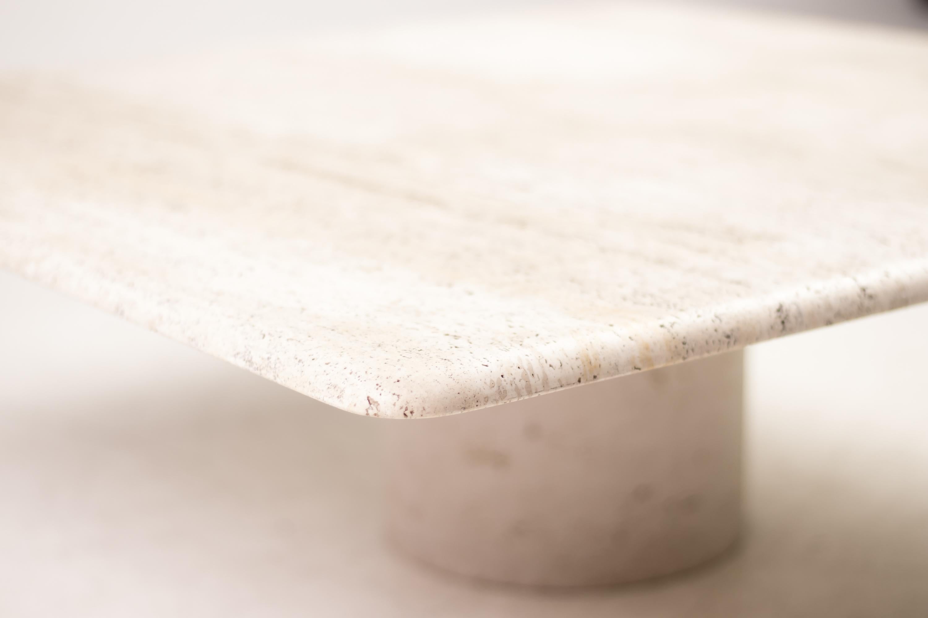 This architectural Up&Up travertine coffee table has a round travertine base that supports a top with trademark Mangiarotti bullnose edge. The travertine has a rich grain and the proportions are beautiful.