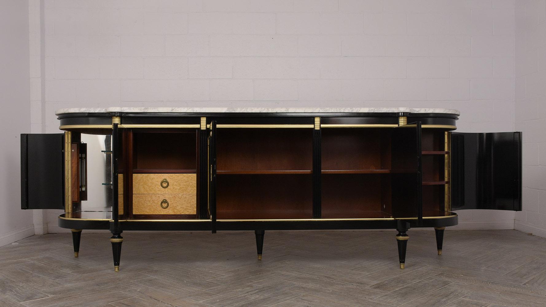 This 1930s French Louis XVI style buffet is made of mahogany wood with an ebonized and lacquered finish. The buffet is topped with a white Carrara and grey vines marble that follows the shape of the buffet and has beveled edges. There are five
