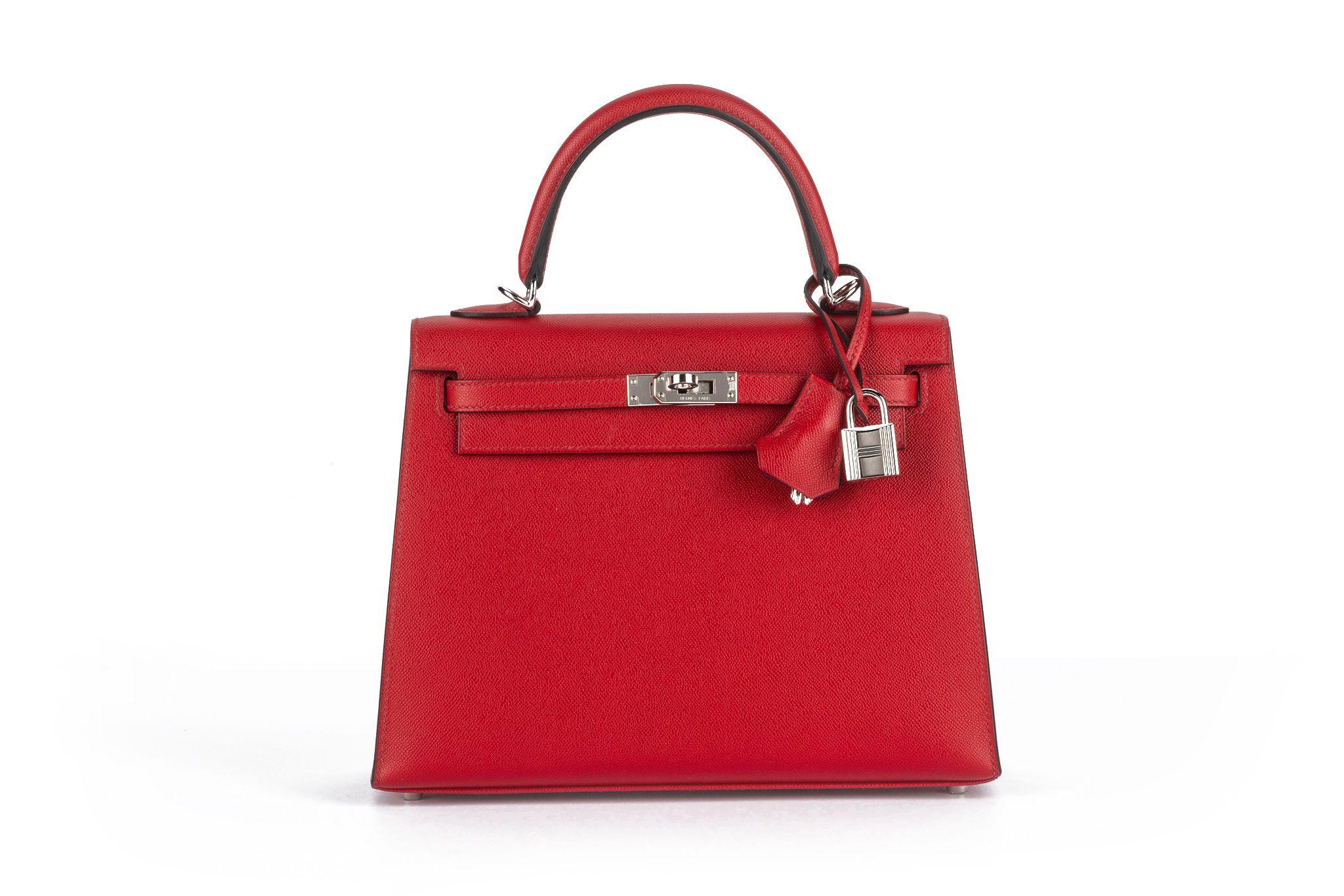 The Kelly 25 verso is in the Sellier style, with palladium hardware, and has tonal stitching, two straps with front toggle closure, and a single rolled handle, the interior is lined with chevre leather. The color is rouge piment with rose pourpre