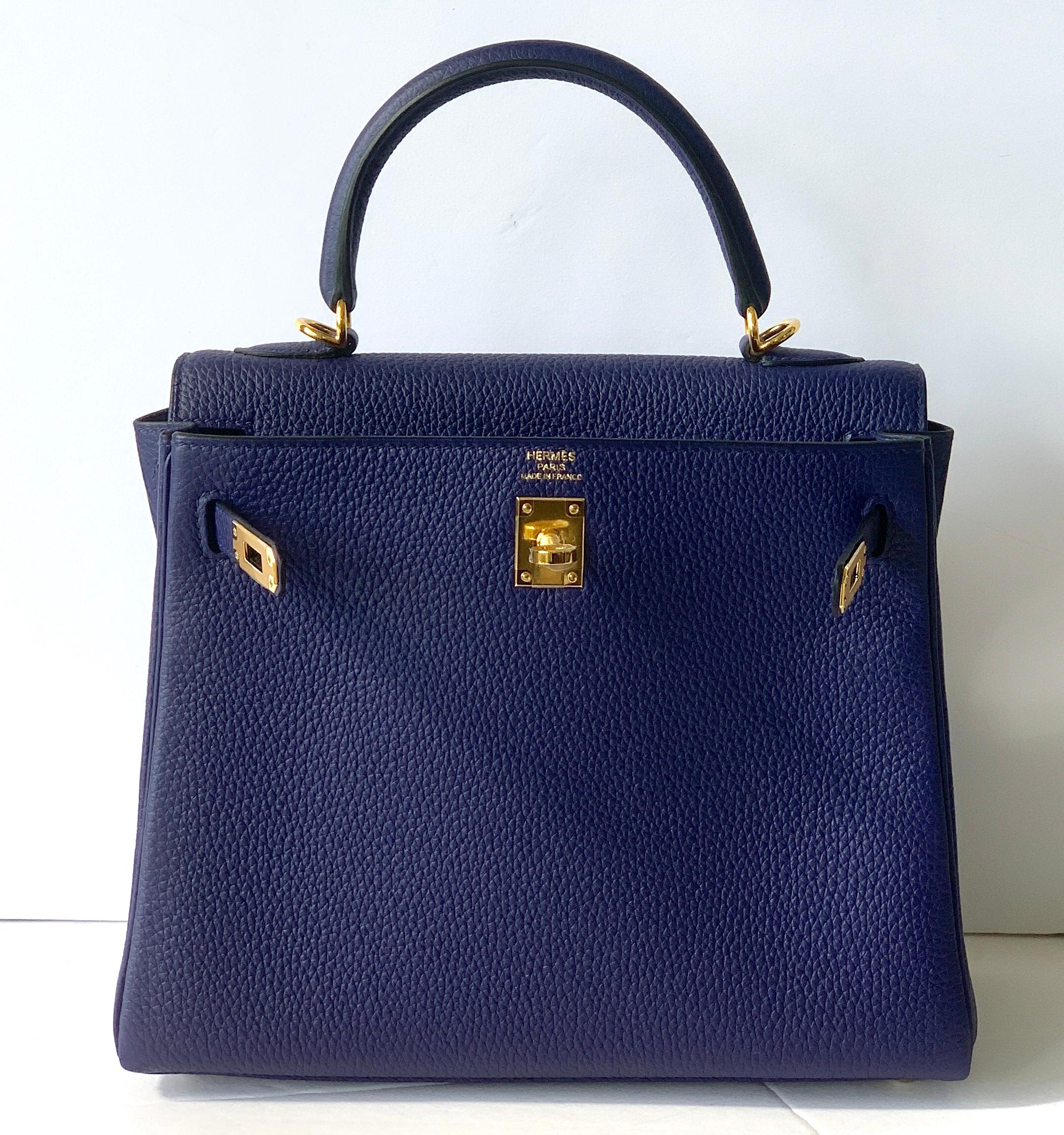 Hermes Blue Encre Kelly 28cm of Togo Leather with gold hardware.

This Kelly has tonal stitching, a front toggle closure, a clochette with lock and two keys and a single rolled handle.

The interior is lined with Chevre and has a zip with an Hermes