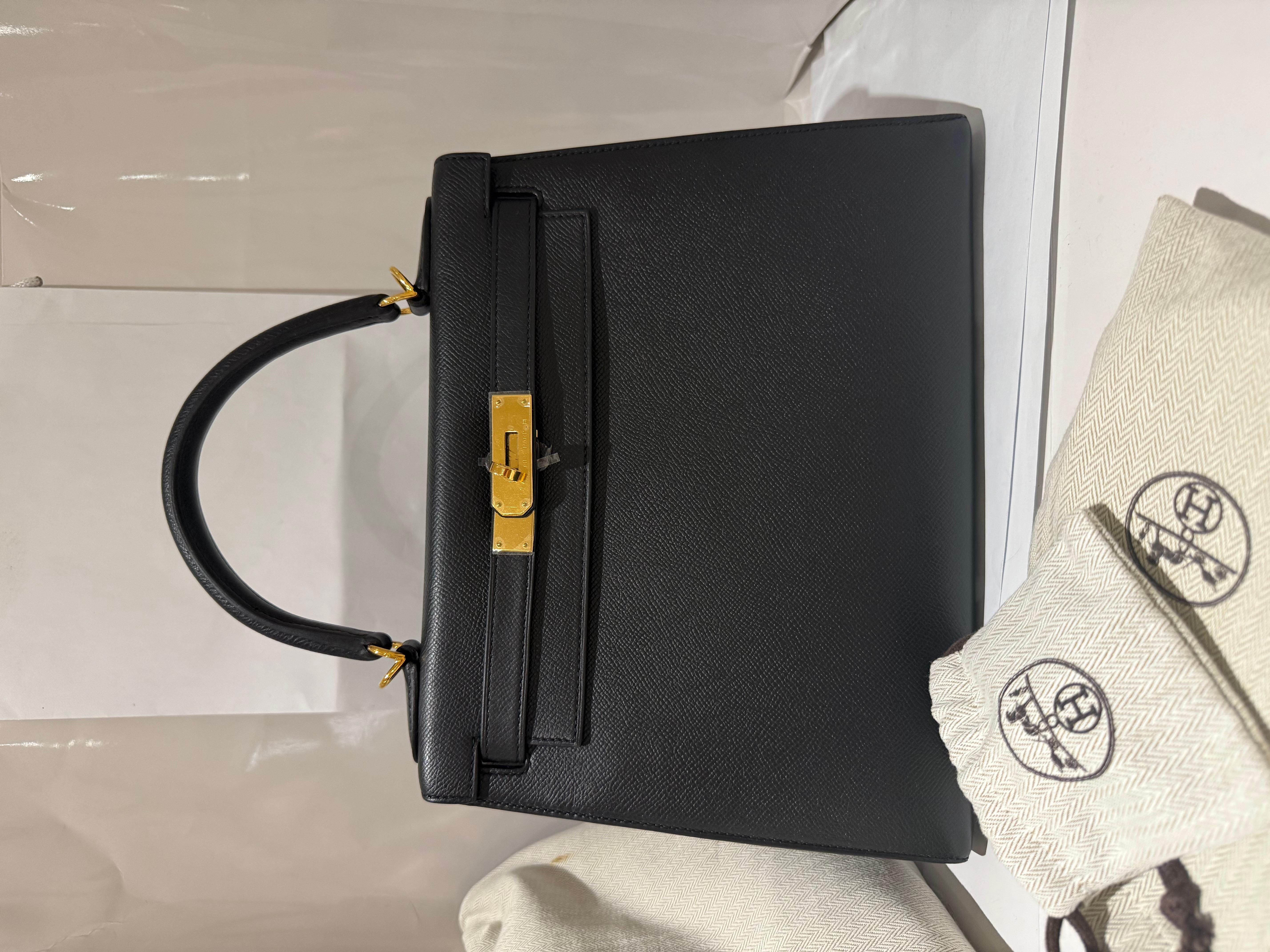 Hermes Kelly 28 Schwarze Tasche aus Epsom-Leder mit goldenen Beschlägen. Diese Tasche ist ein echtes Statement für jede Gelegenheit! Sie wird mit langem, abnehmbarem Armband, Clochette, Schloss und Schlüssel, Staubbeutel und Box geliefert. 

Die