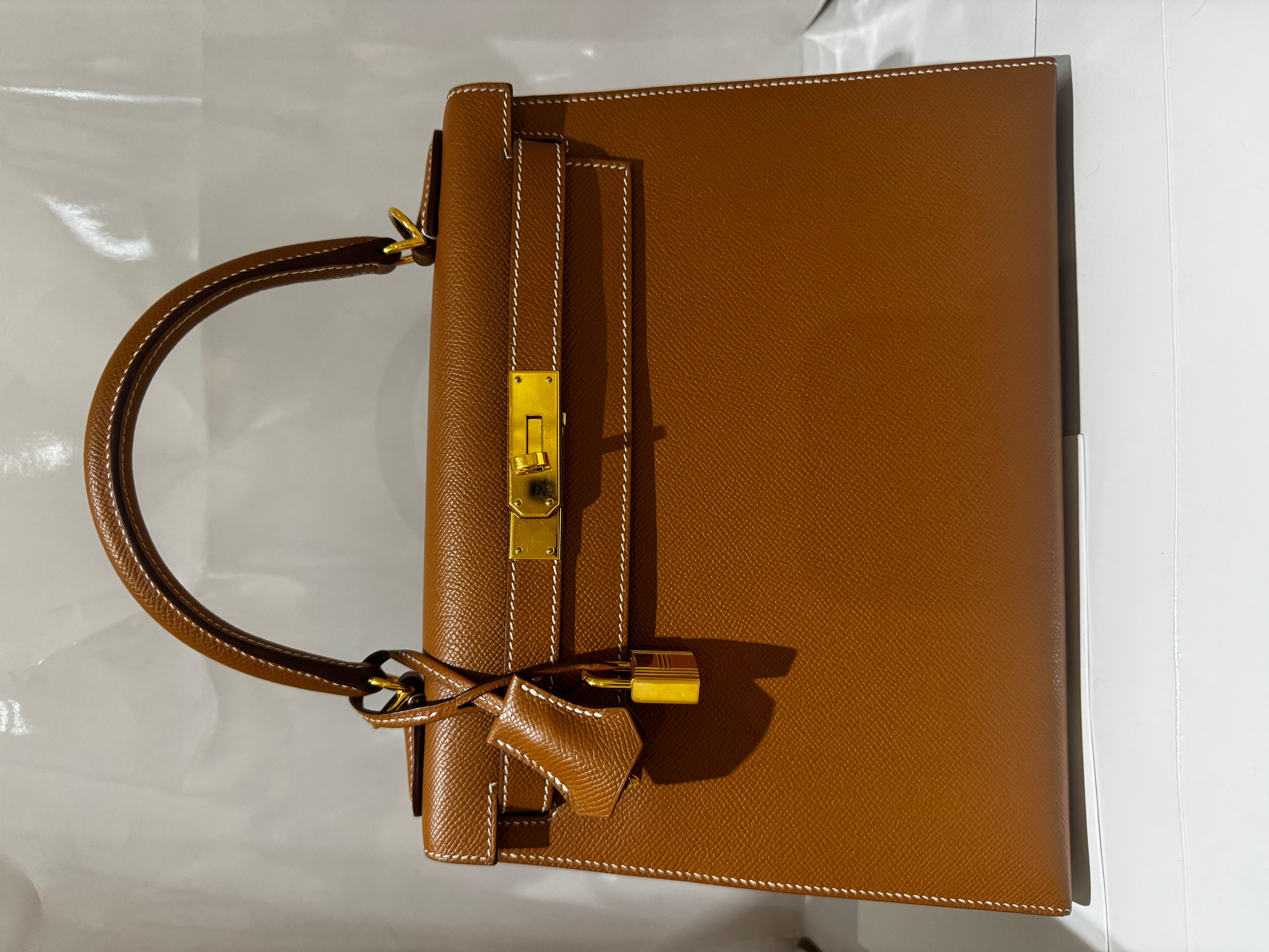 Hermès Kelly 28 Gold Epsom Sellier with Gold Hardware handbag , 2023

Interior is lined with tonal leather
Includes detachable strap, clochette with lock and keys, dust bag, raincoat, and box

Dimensions

Height: 8.66 inches / 22 cm
Width: 11.02