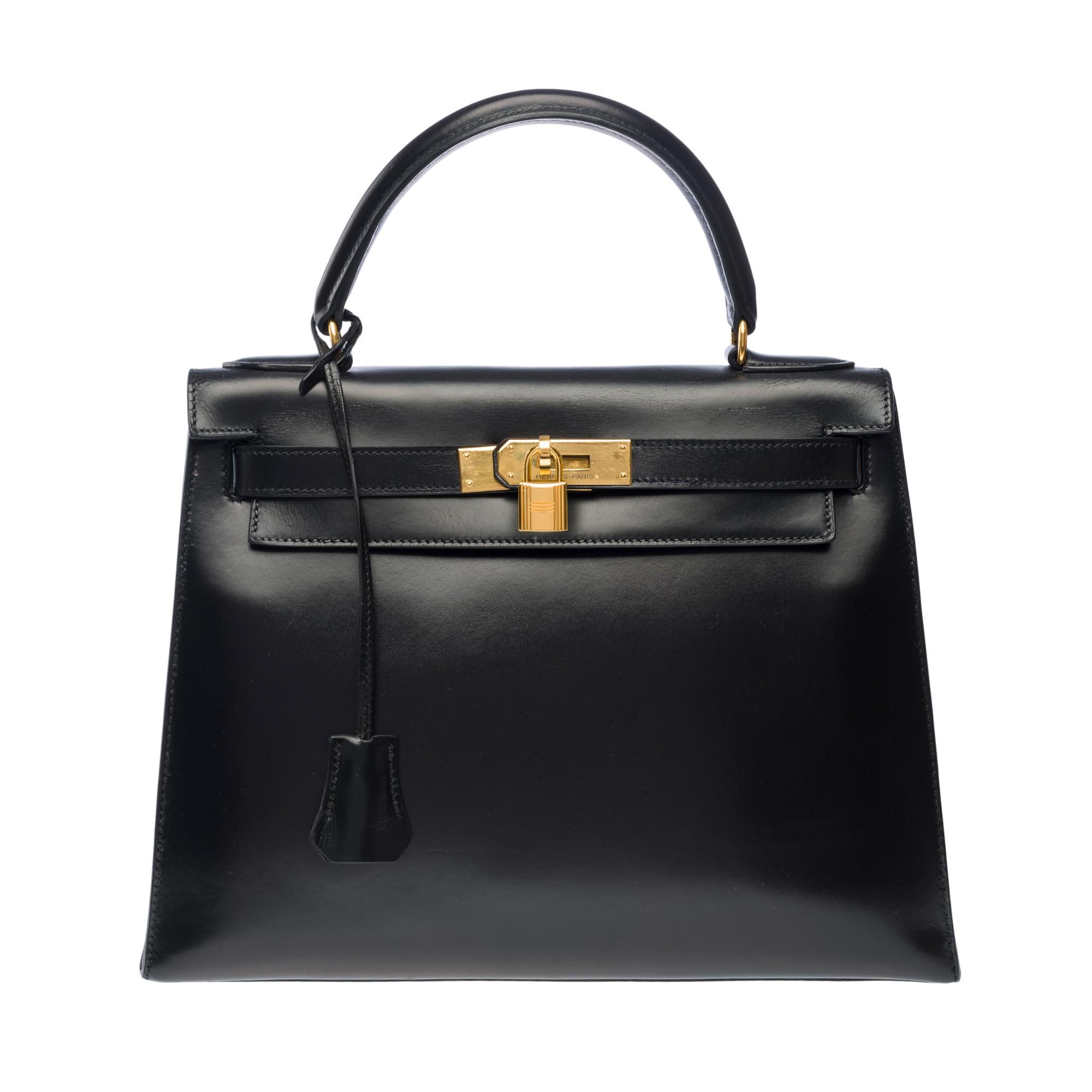 Magnífico bolso Hermès Kelly 28 sellier en piel de becerro caja negra,   ribete metálico dorado, asa de caja de cuero negro para llevar en la mano

Cierre con solapa
Forro interior de cuero negro,   un bolsillo con cremallera, dos bolsillos de