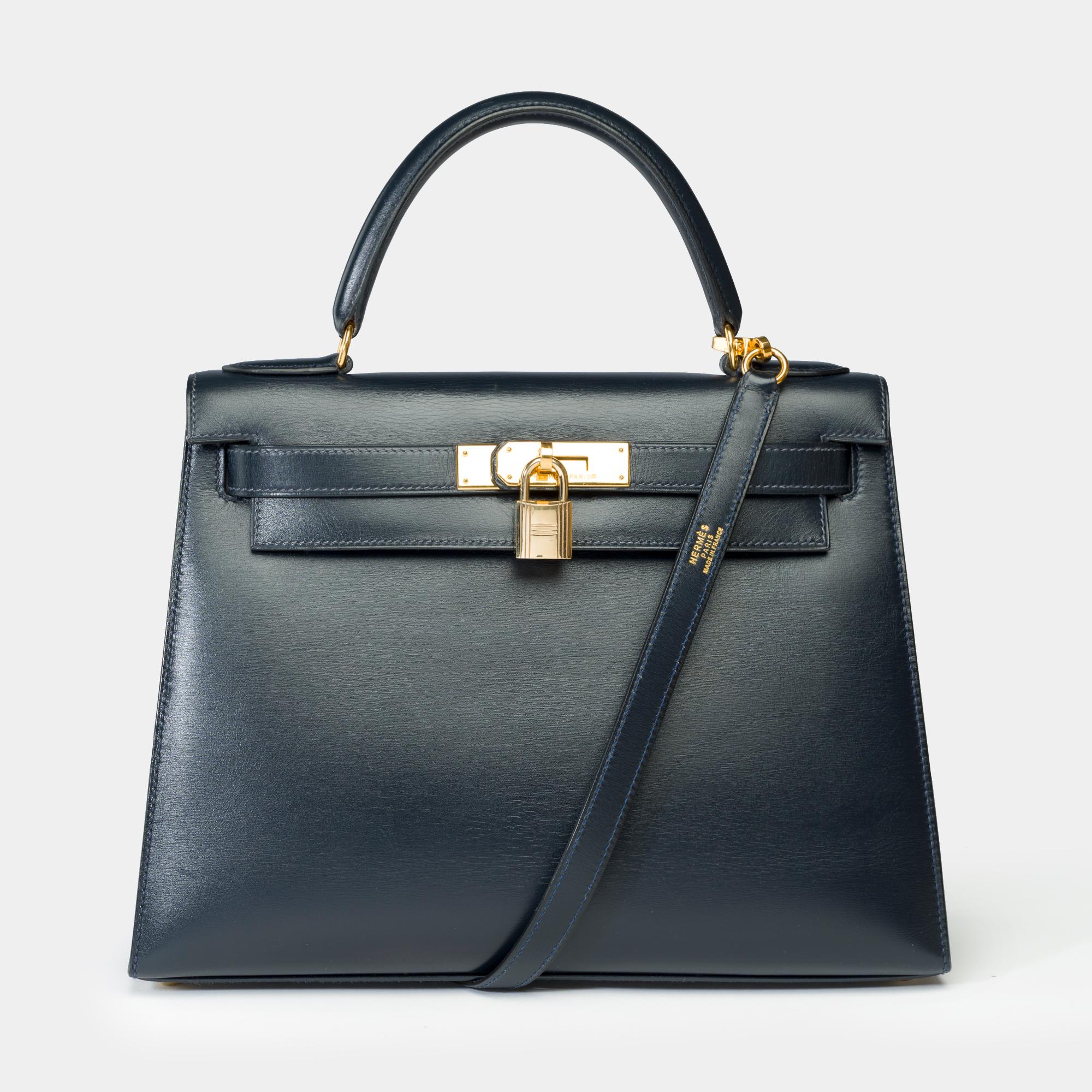 Exceptional​ ​Hermes​ ​Kelly​ ​28​ ​Sellier​ ​handbag​ ​strap​ ​in​ ​Navy​ ​Blue​ ​Box​ ​calf​ ​leather,​ ​with​ ​gold​ ​metal​ ​trim,​ ​blue​ ​leather​ ​handle,​ ​and​ ​removable​ ​navy​ ​leather​ ​shoulder​ ​strap​ ​allowing​ ​for​ ​hand,​