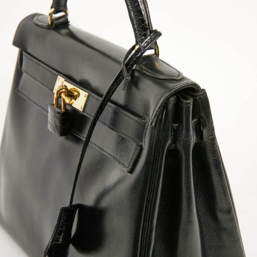 This beautiful vintage bag Kelly 28 in black leather Box. It has been renovated. The leather strap has been replaced by a crocodile strap. The jewelry is in metal gold plated. In very good condition. Dimensions: length 28 x hight 21 x deep 11 cm.