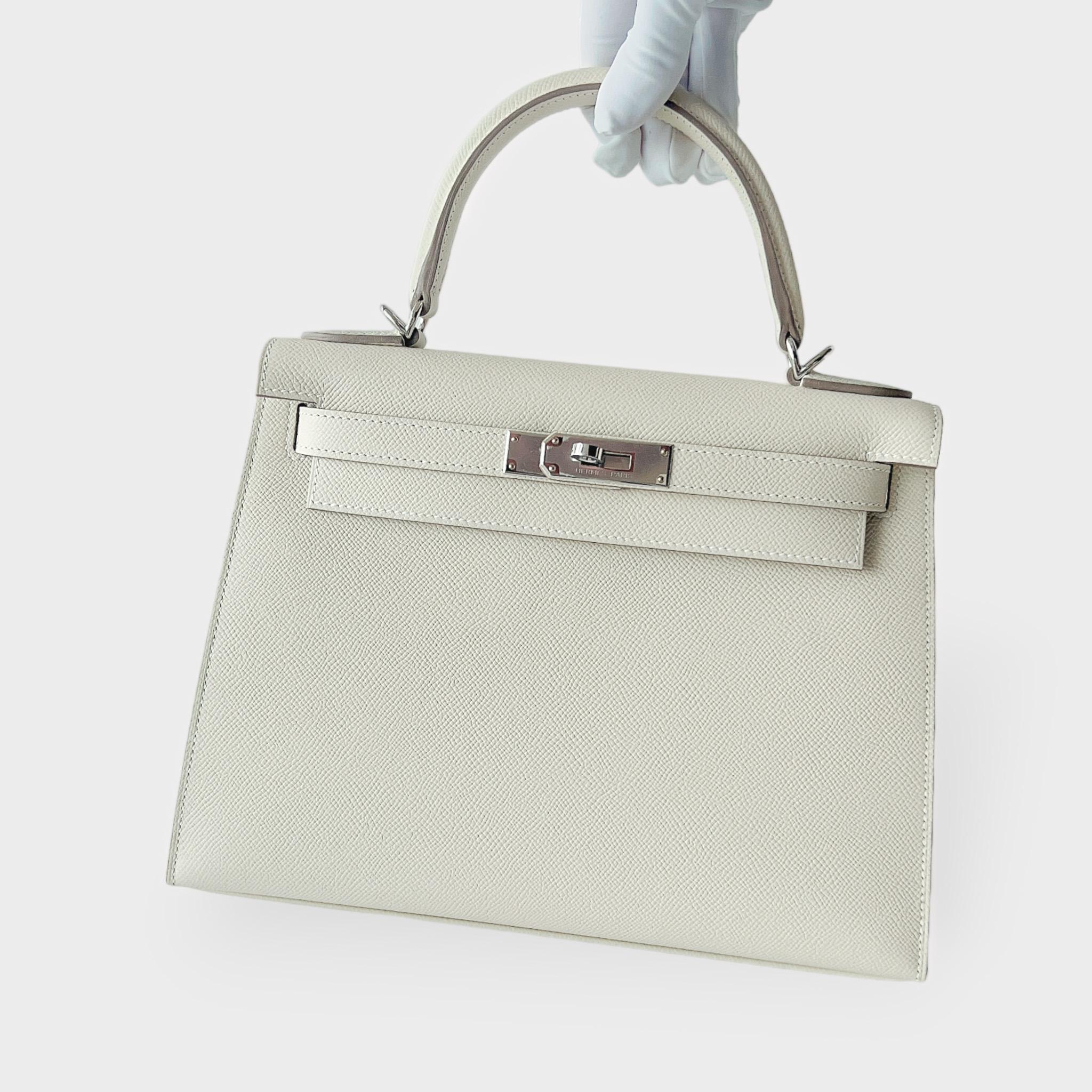 Shop this elegant Hermès Kelly 28 In Craie with Palladium Hardware. It is unused in pristine condition, purchased in 2023. This Hermès Kelly 28cm Bag comes in Craie, which is the perfect neutral slightly creamy white for any season. The bag comes