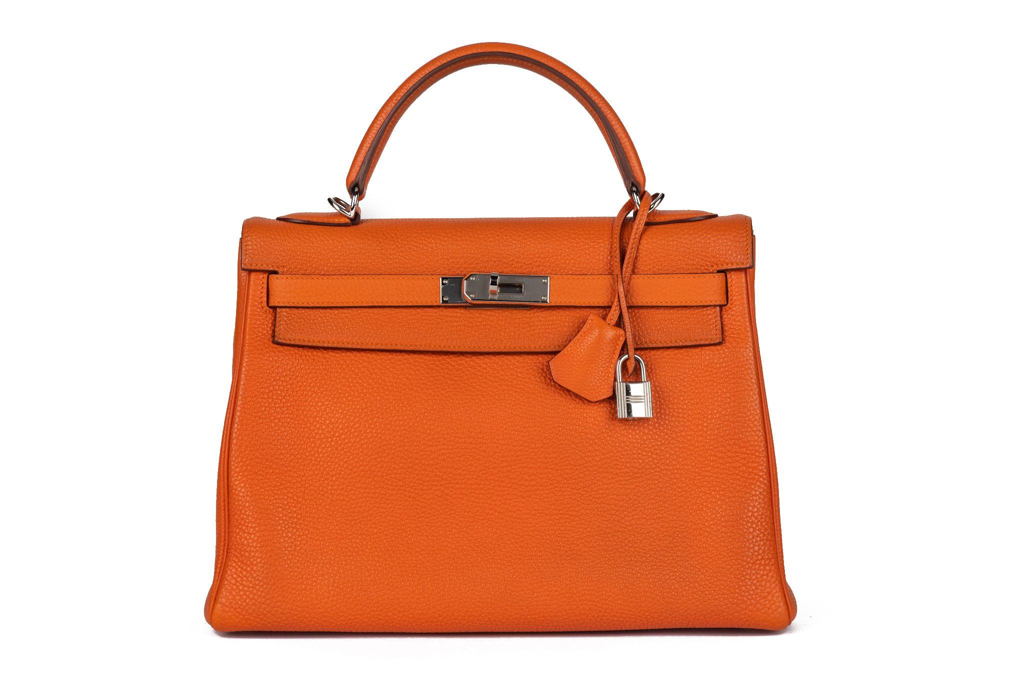 Hermès Kelly 32 retourne in Orange taurillon clemence leather, palladium hardware . The piece is in excellent condition and shows the date stamp K. The bag comes with the full set: clochette, tirette, lock, keys, dust cover, rain jacket and box.