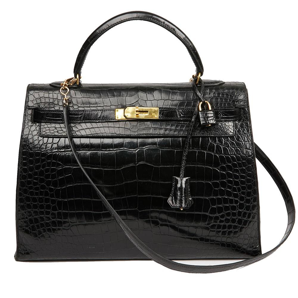 Kelly 35 bag is made of black Porosus crocodile, lined with smooth leather. Inside is a large flat pocket on one side and two small on the other side. The trimmings are in gold metal. The handle as well as the bell and padlock have been changed. A
