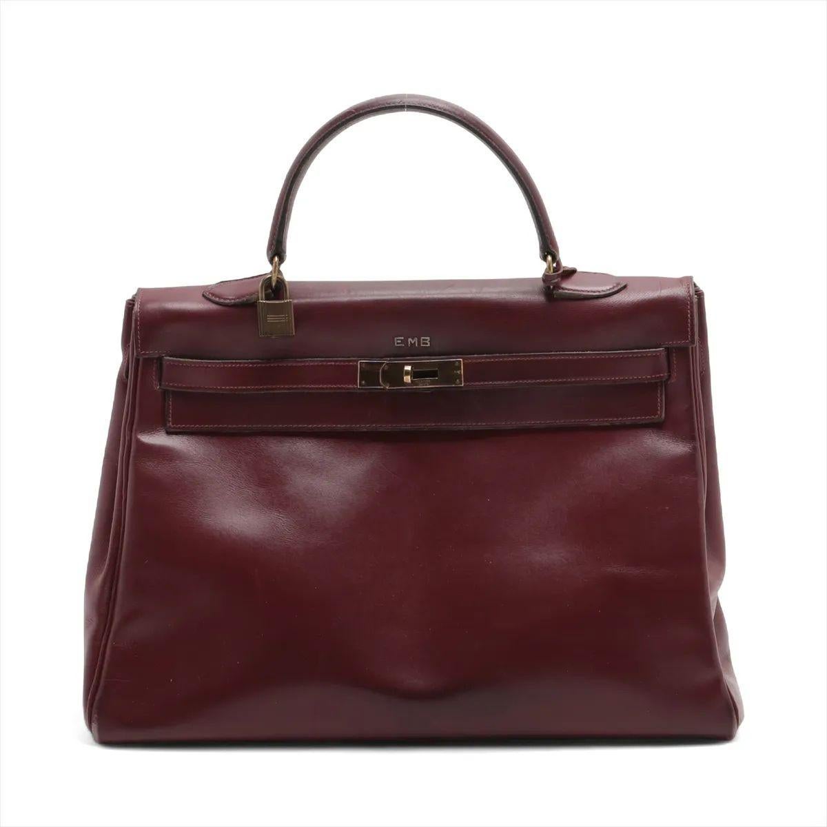 The Hermès Kelly 35 Le Tournay Leather Handbag in Rouge H is a timeless symbol of elegance and sophistication. Crafted from luxurious leather in the house’s iconic deep burgundy hue, it features the structured silhouette that has made the Kelly an