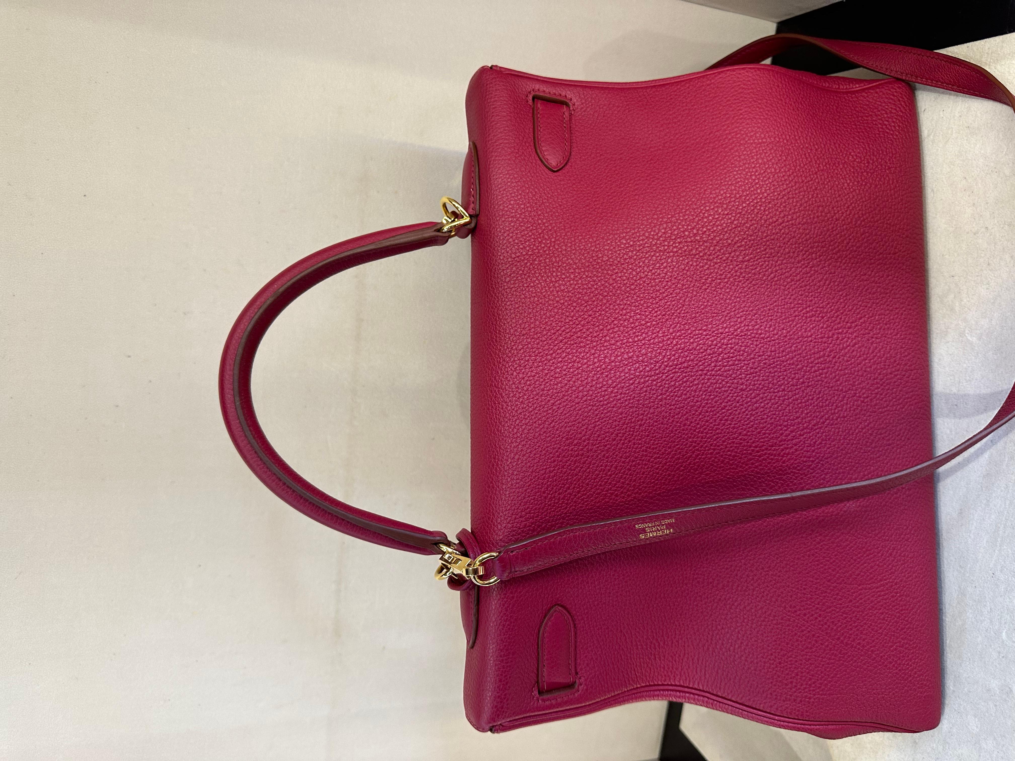 Sac Kelly Hermès en couleur Rubis, cuir togo et quincaillerie dorée. Ce magnifique sac à main est de couleur rouge, ce qui lui confère une grande visibilité tout en restant très polyvalent. Le cuir Togo est très résistant et luxueux. Le sac Kelly