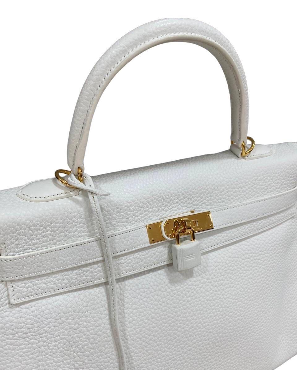 Hermès signed bag, Kelly model, size 25, made of white togo leather with golden hardware.

Equipped with a flap with interlocking closure with padlock covered in leather, internally lined in smooth white leather, very roomy.

Equipped with a central