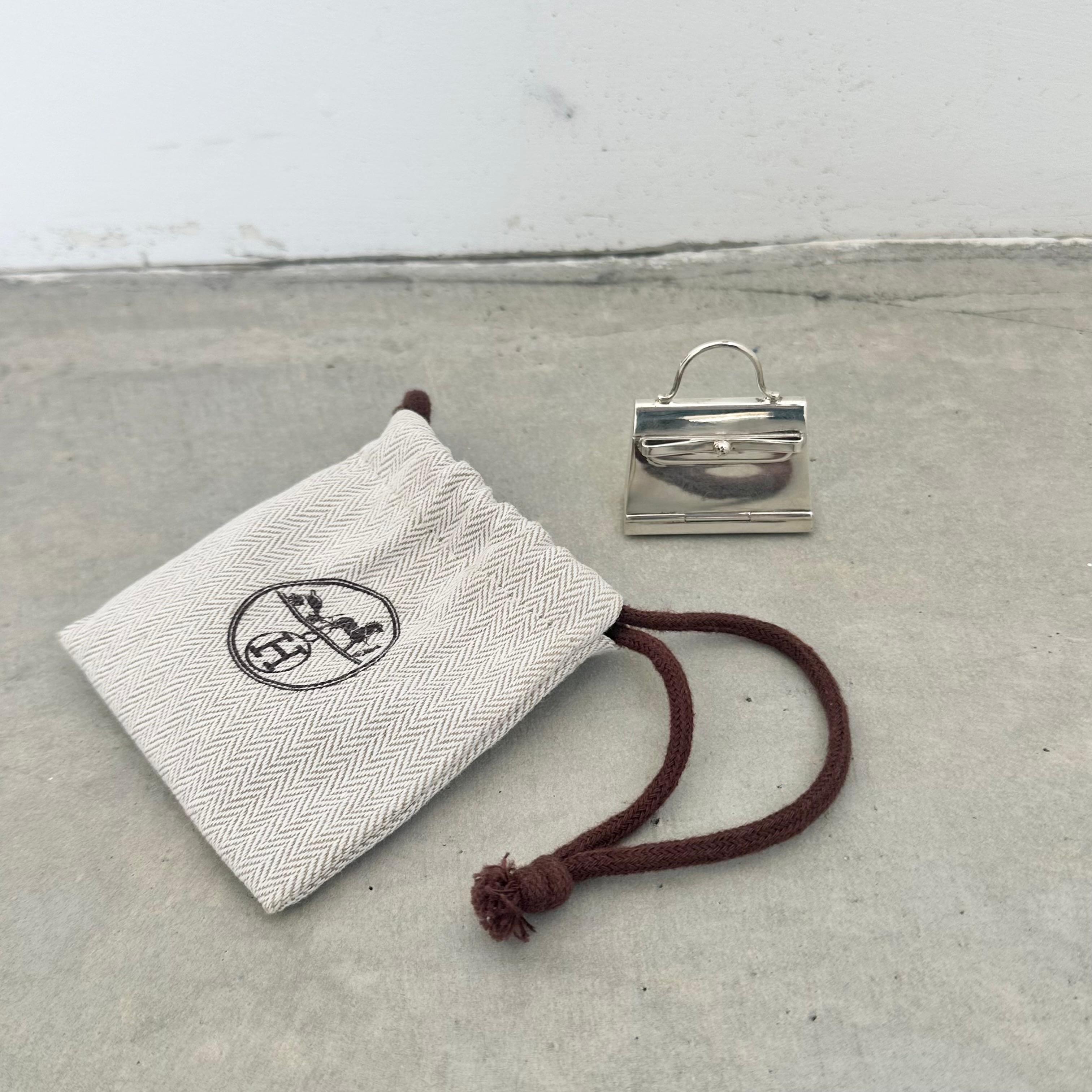 Mini Hermés pill box in the shape of the iconic Kelly Bag. This tiny sterling silver jewel opens up from the front. Originally made as a pill box, but can be used as a small accessory or to hold any tiny treasures. 

Beautiful accent piece to