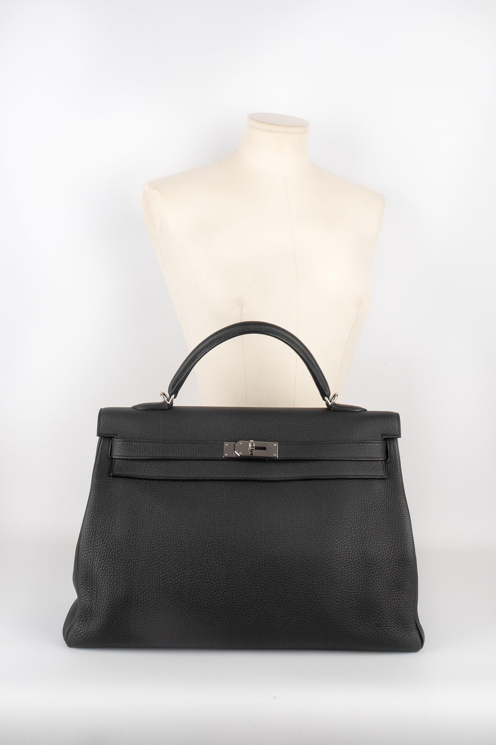 Hermes - (Made in France) 40 cm black togo calfskin bag, Kelly Retourne style with palladium-plated silvery metal fastener and ties, a handle, keys under a tiny cloche, and a padlock. The Retourne design is made of supple leather, as if it was