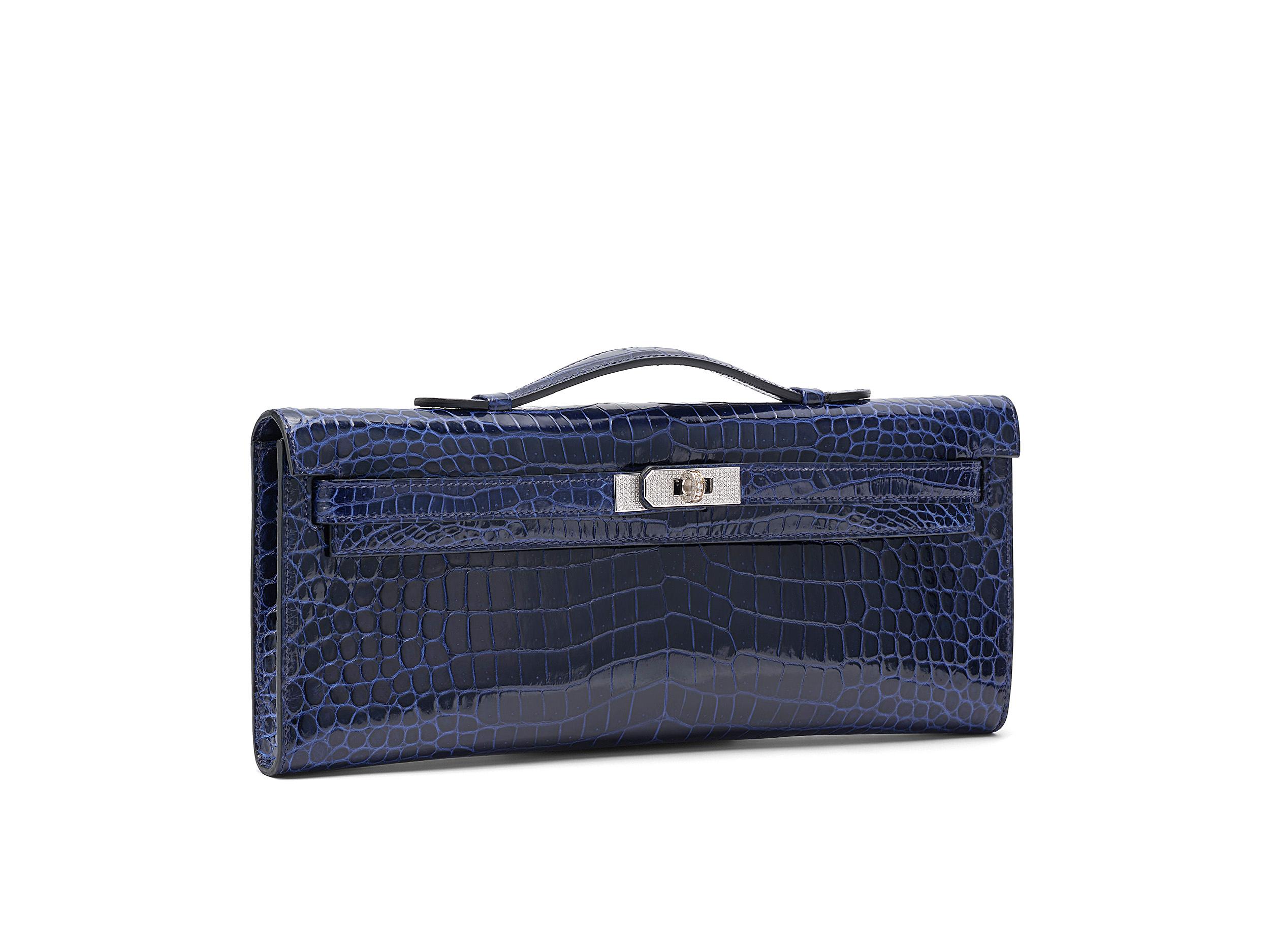 Hermès Kelly Cut in bleu saphir and shiny porosus crocodile leather. The hardware is set with diamonds, but does not come from Hermès. The original Hermès hardware is included and can be replaced. The bag is in very good condition, there are only