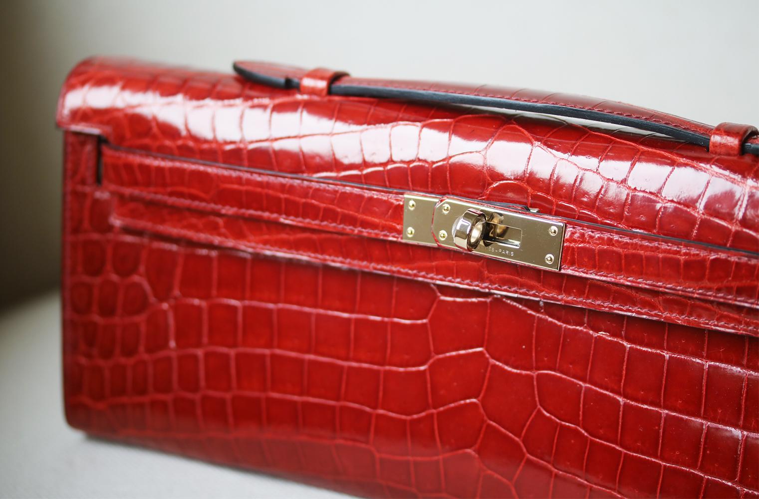 Hermès Kelly Cut Niloticus Crocodile Clutch with gold-plated hardware. Single flat top handle. Tonal leather lining. Single slit pocket at interior wall. Turn-lock closure at front. Colour: burgundy-red. Does not come with a dustbag or box. 