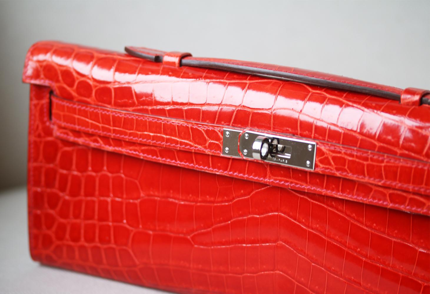 Hermès Kelly Cut Niloticus Crocodile Clutch with palladium hardware. Single flat top handle. Tonal leather lining. Single slit pocket at interior wall. Turn-lock closure at front.  Colour: orange. Does not come with a dustbag or box. 

Dimensions: W