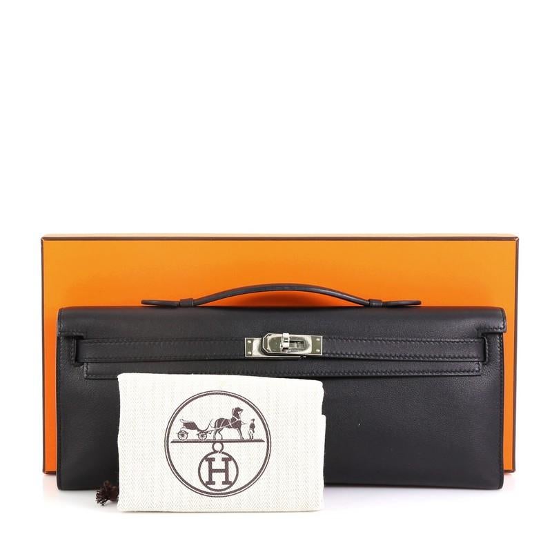 This Hermes Kelly Cut Pochette Swift, crafted in Noir black Swift leather, features a top handle, frontal flap, and palladium hardware. Its turn-lock closure opens to a Noir black Swift leather interior. Date stamp reads: C (2018). 

Condition:
