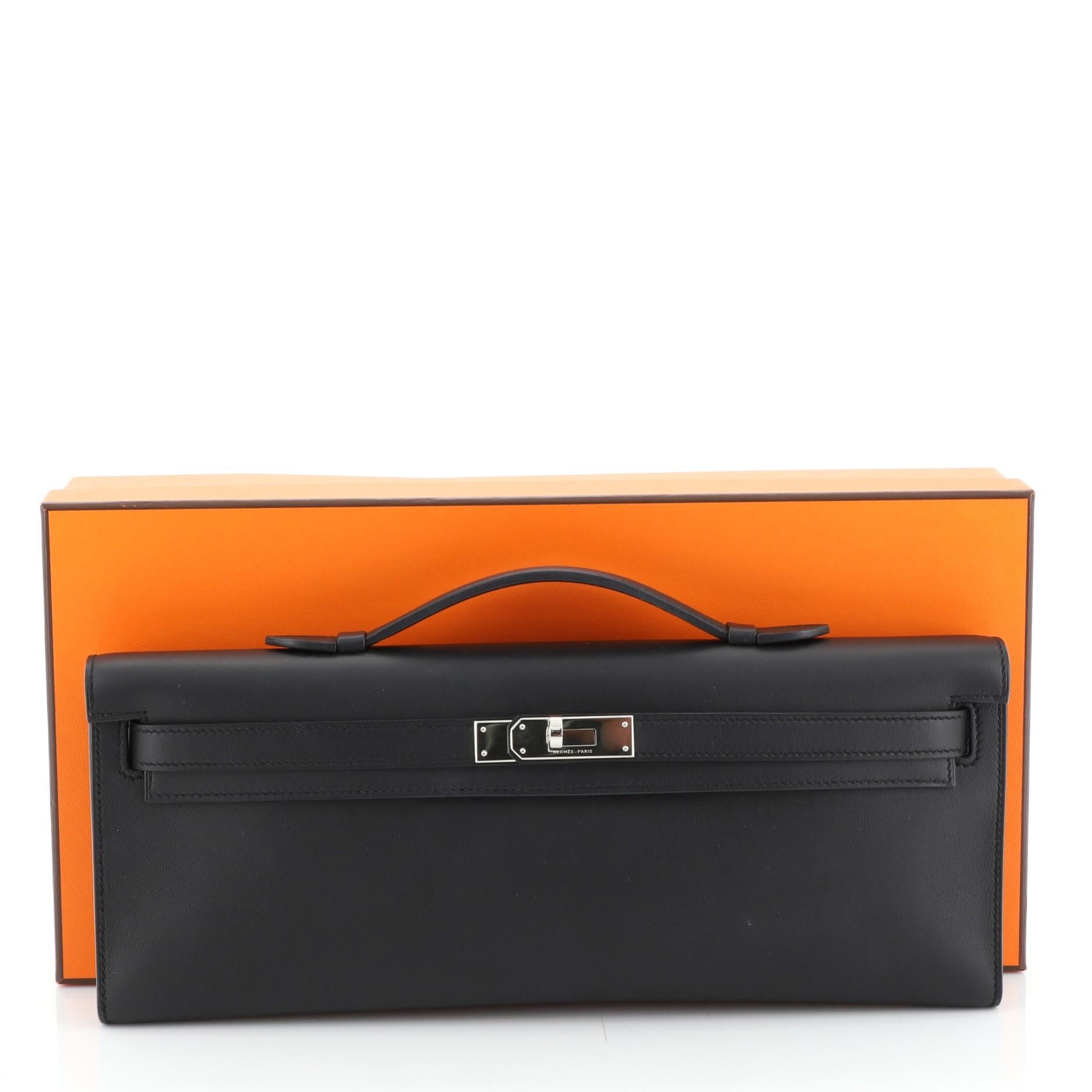 This Hermes Kelly Cut Pochette Swift, crafted in Noir black Swift leather, features a top handle, frontal flap, and palladium hardware. Its turn-lock closure opens to a Noir black Chevre leather interior. Date stamp reads: T (2015).

Condition: