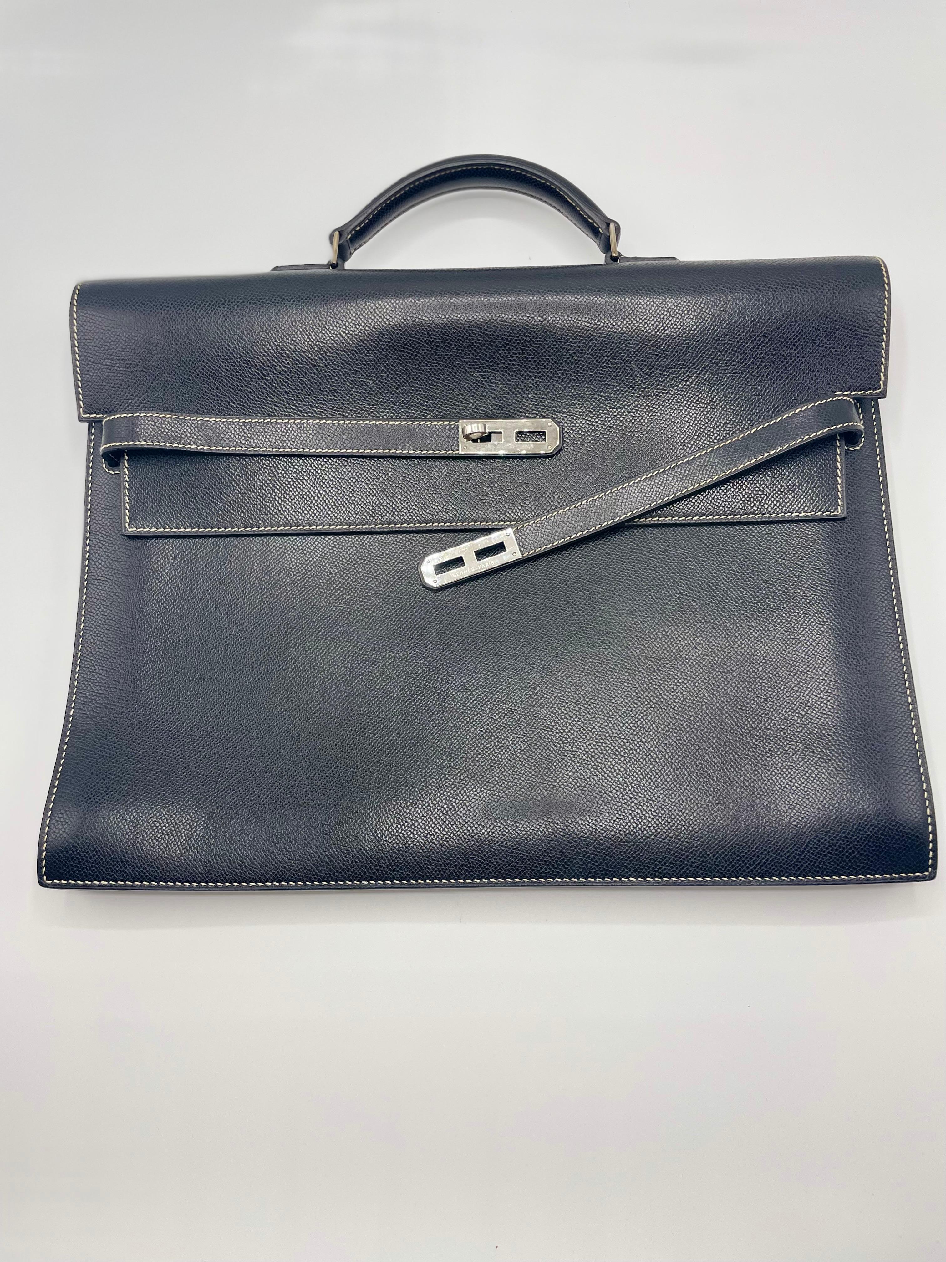 This fashionable handbag is fashioned from supple dark blue calfskin leather. The case has a robust leather top handle with silver palladium links, a crossing flap with a strap closing, and a Kelly Palladium turn lock. A bell with keys is attached