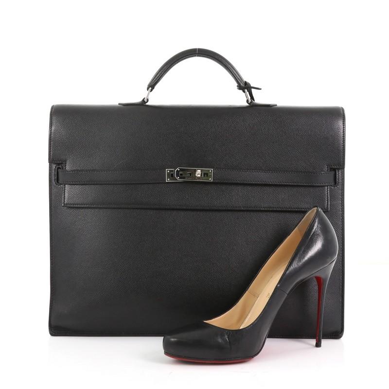 This Hermes Kelly Depeche Handbag Epsom 38, crafted from black noir epsom leather, features a short rolled top handle, accordion-like side gussets, and palladium-tone hardware. Its belt and turn-lock closure opens to a black raw leather interior