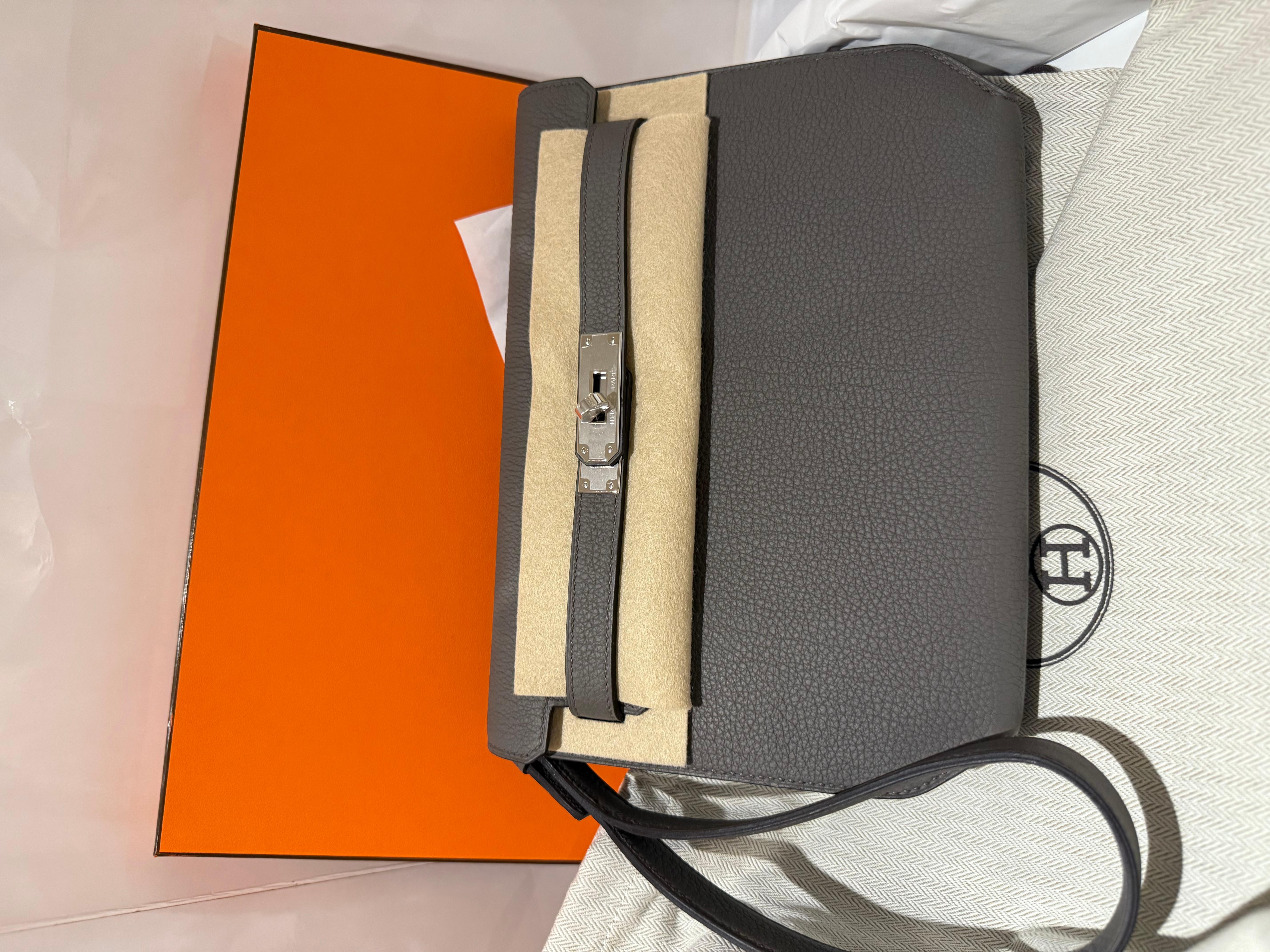 Bolso Hermes Kelly Depeches 25 en color Etain, cuero togo con herrajes paladio. Producción del sello K 2025.
Correa de muñeca desmontable.

Nuevo a estrenar con caja, bolsa guardapolvo y recibo 