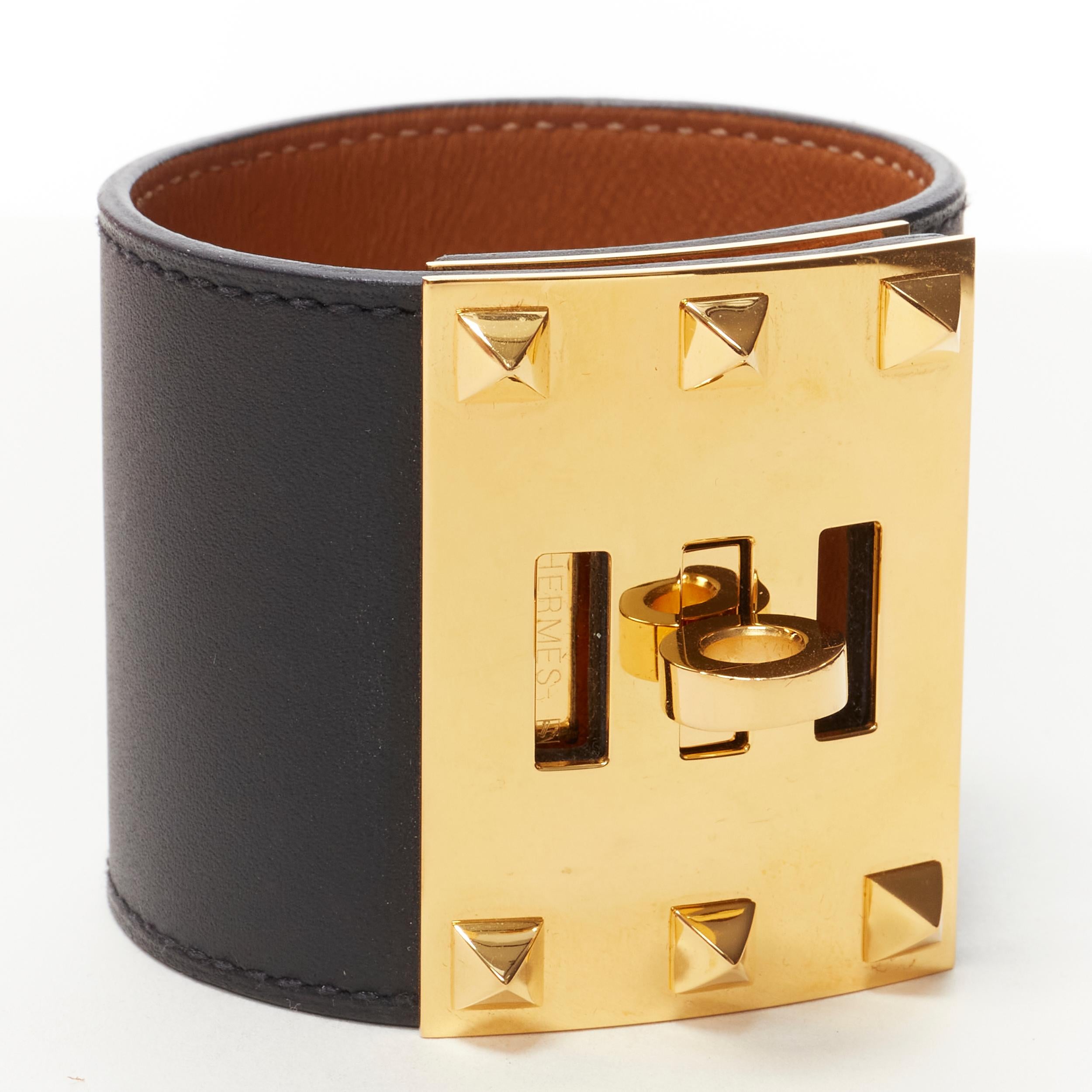 HERMES Kelly Dog Extreme 18k yellow gold plated brass turnlock stud black cuff 
Reference: KEDG/A00016 
Brand: Hermes 
Collection: Kelly 
Material: Leather 
Color: Black 
Pattern: Solid 
Closure: Turnlock 
Extra Detail: 18K yellow gold-plated brass.
