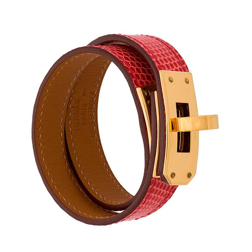Crafted in France from a pink lizard skin, this rare edition of the signature Hermès Kelly double tour bracelet features a flip-lock closure, accented by gold-tone palladium hardware, a tan calfskin lining and a wrap-around leather strap design,