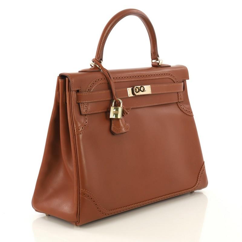 This Hermes Kelly Ghillies Handbag Fauve Tadelakt with Gold Hardware 35, crafted from Fauve brown Tadelakt leather, features a single looped top handle, broguing at top and bottom, protective base studs, and gold hardware. Its turn-lock closure